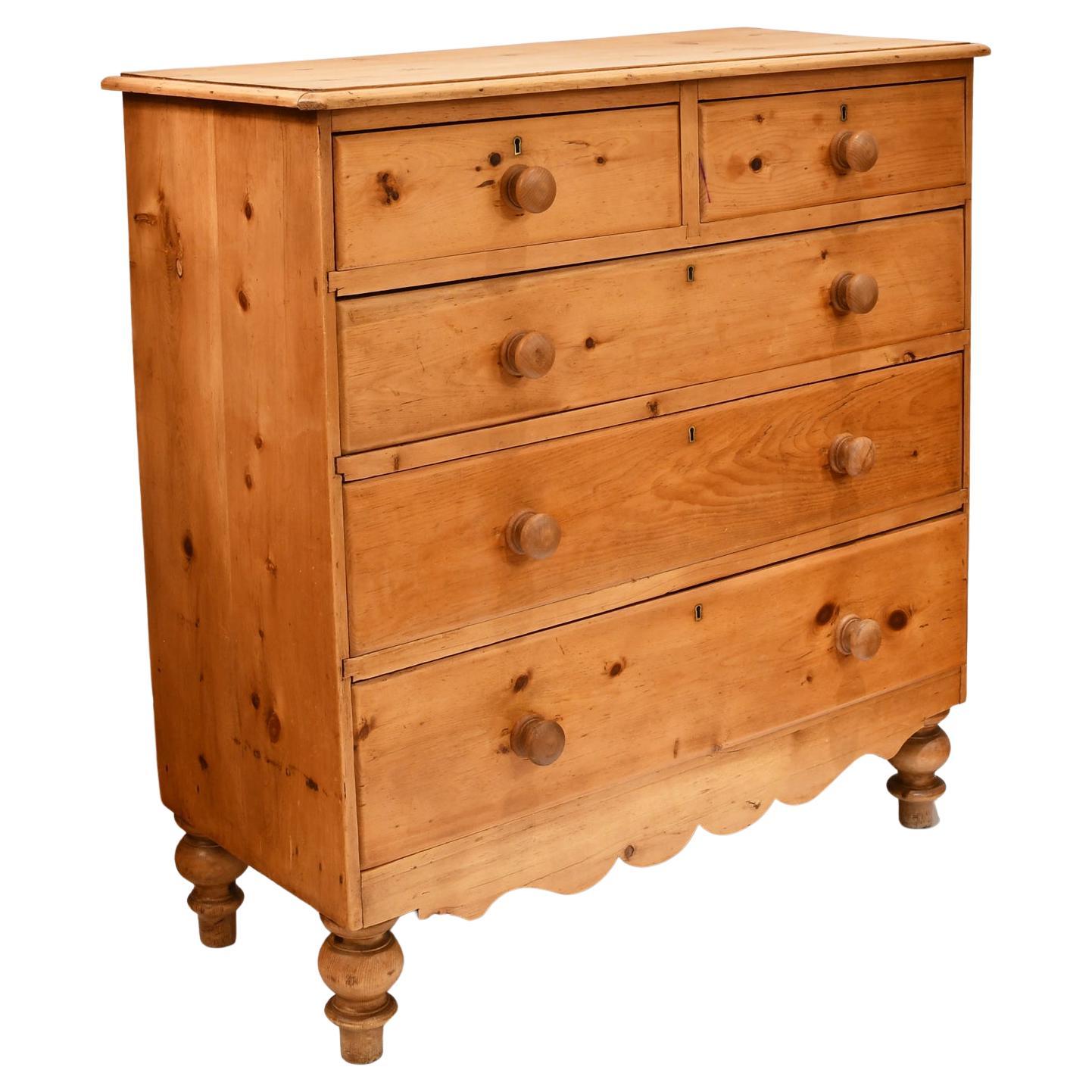 Une exceptionnelle commode anglaise 2 sur 3 en pin rustique avec des boutons en bois tournés, des pieds tulipes tournés d'origine et un tablier festonné. 2 petits tiroirs sur 3 longs tiroirs offrent un grand espace de rangement. La serrure du tiroir