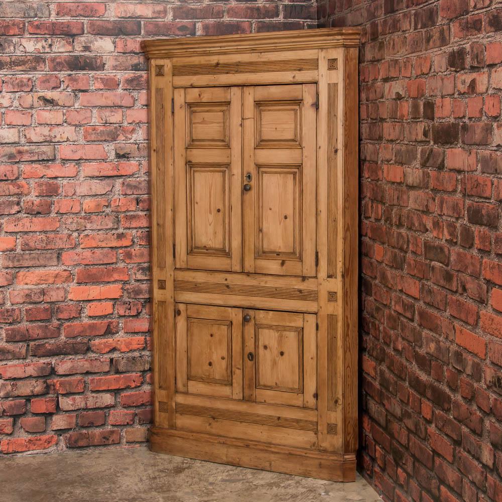 The character of this English corner cupboard is revealed in the aged patina of the pine with it's raised panels and carved moldings. The gray painted interior has fixed shelves and has been given a wax finish inside and out, bringing out the warmth