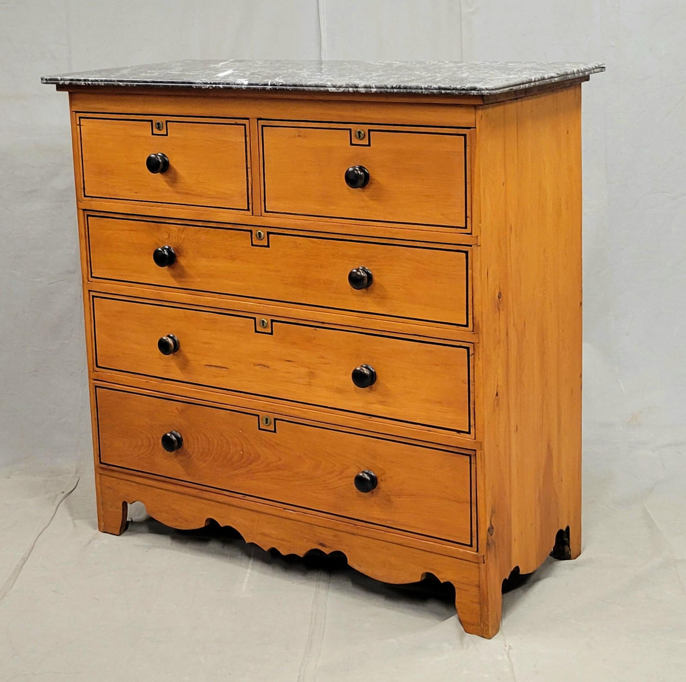 Commode classique en pin anglais de la fin du XIXe siècle, avec doublure française peinte en noir sur le périmètre des façades des tiroirs et un plateau amovible en marbre noir et blanc. Les boutons tournés ébonisés d'origine et les entrées de clé