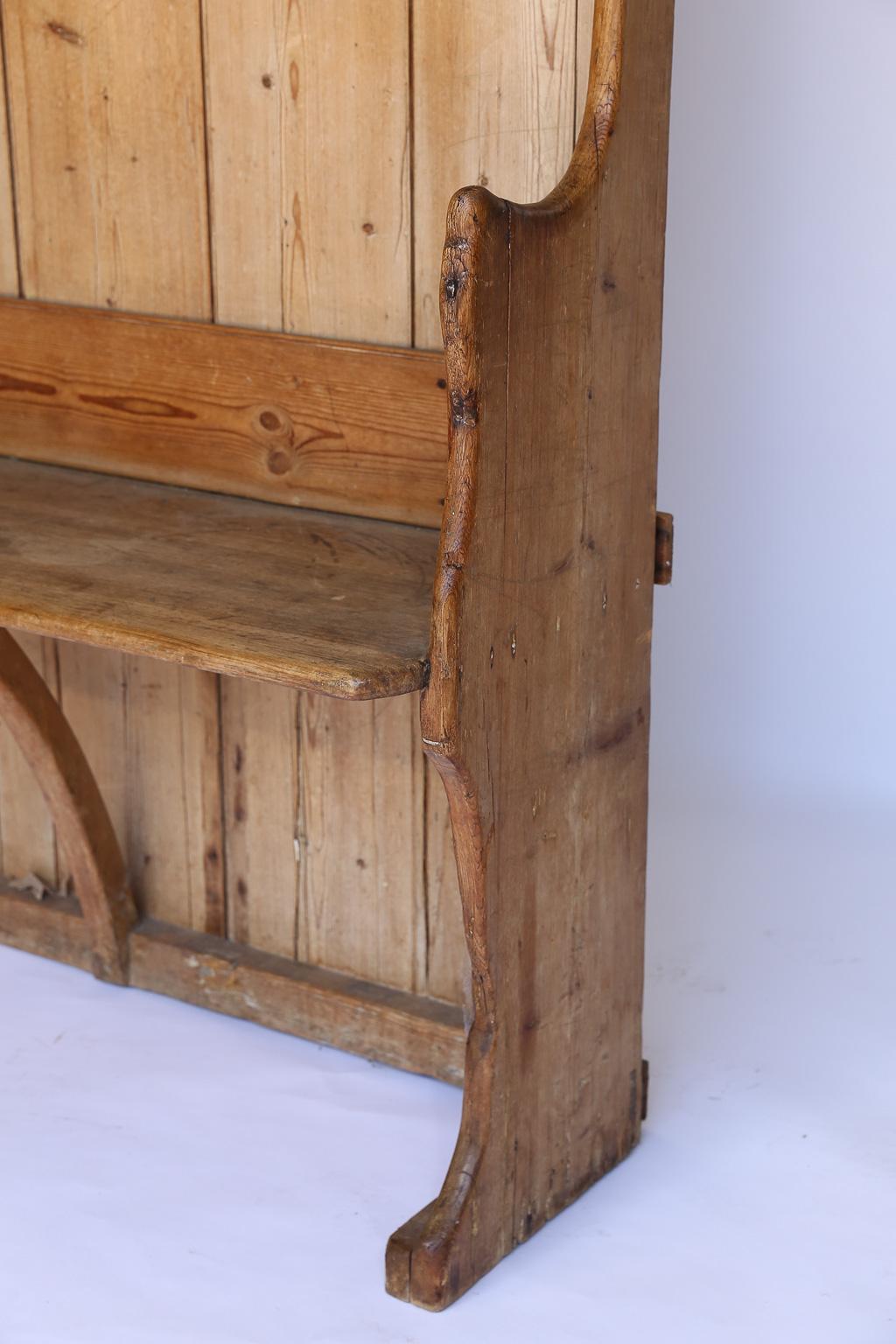 This antique pine settle has the perfect dimensions for a hallway. Found in England and made of pine, the piece is freestanding and sturdy. The settle has a beautiful waxed patina.