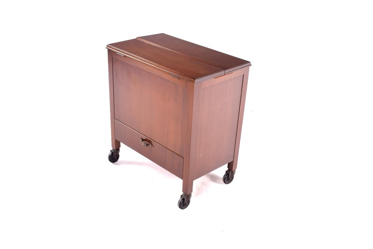 A 1960s mahogany cocktail cabinet having a hinged flip top enclosing pop up top drink cabinet raised on castors. This elegant pop up bar is ready to be offered up with a presentation of sheer sophistication. Lifting the top, the interior bar rises