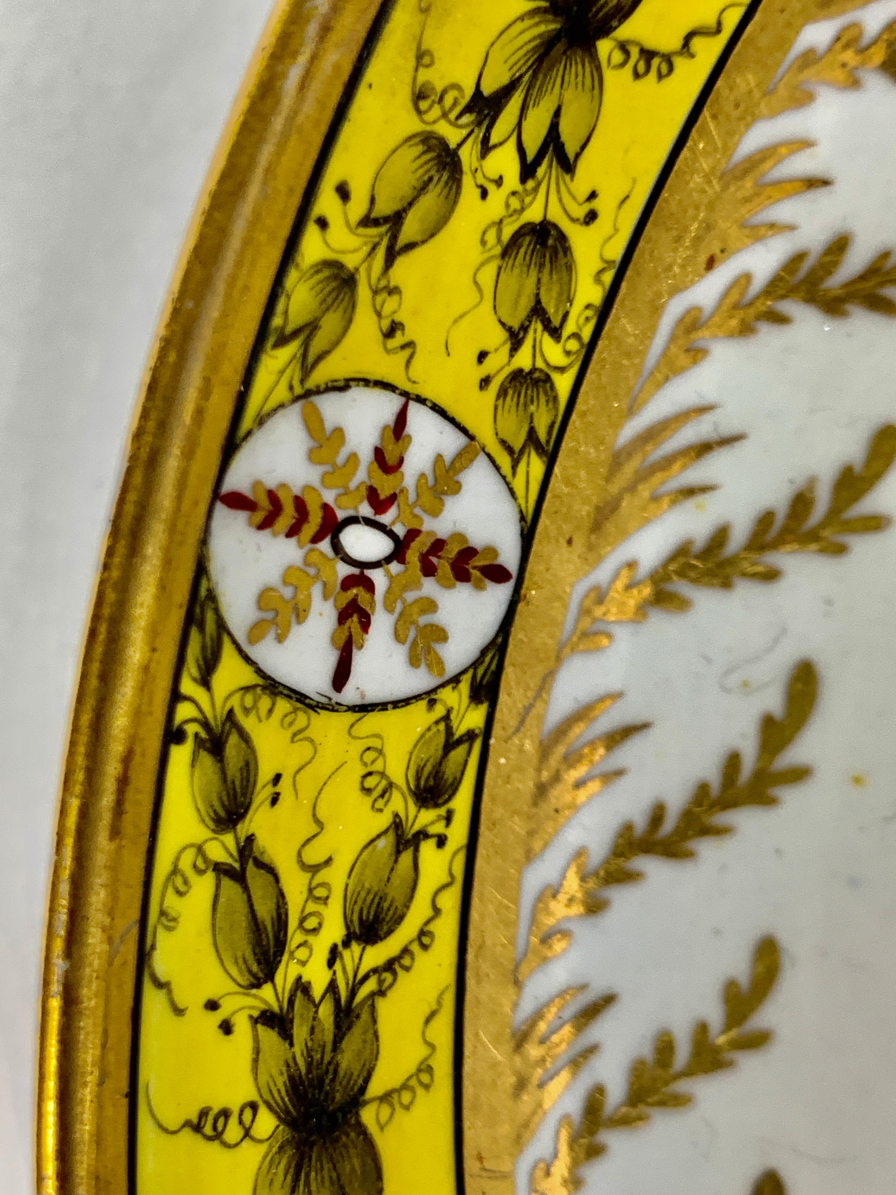 The border of this antique English porcelain dish has an exquisite yellow ground with an eye-catching design.
The neoclassical decoration is hand-painted. We see flower buds painted in grisaille, crisscrossing oval medallions.
Just beneath the
