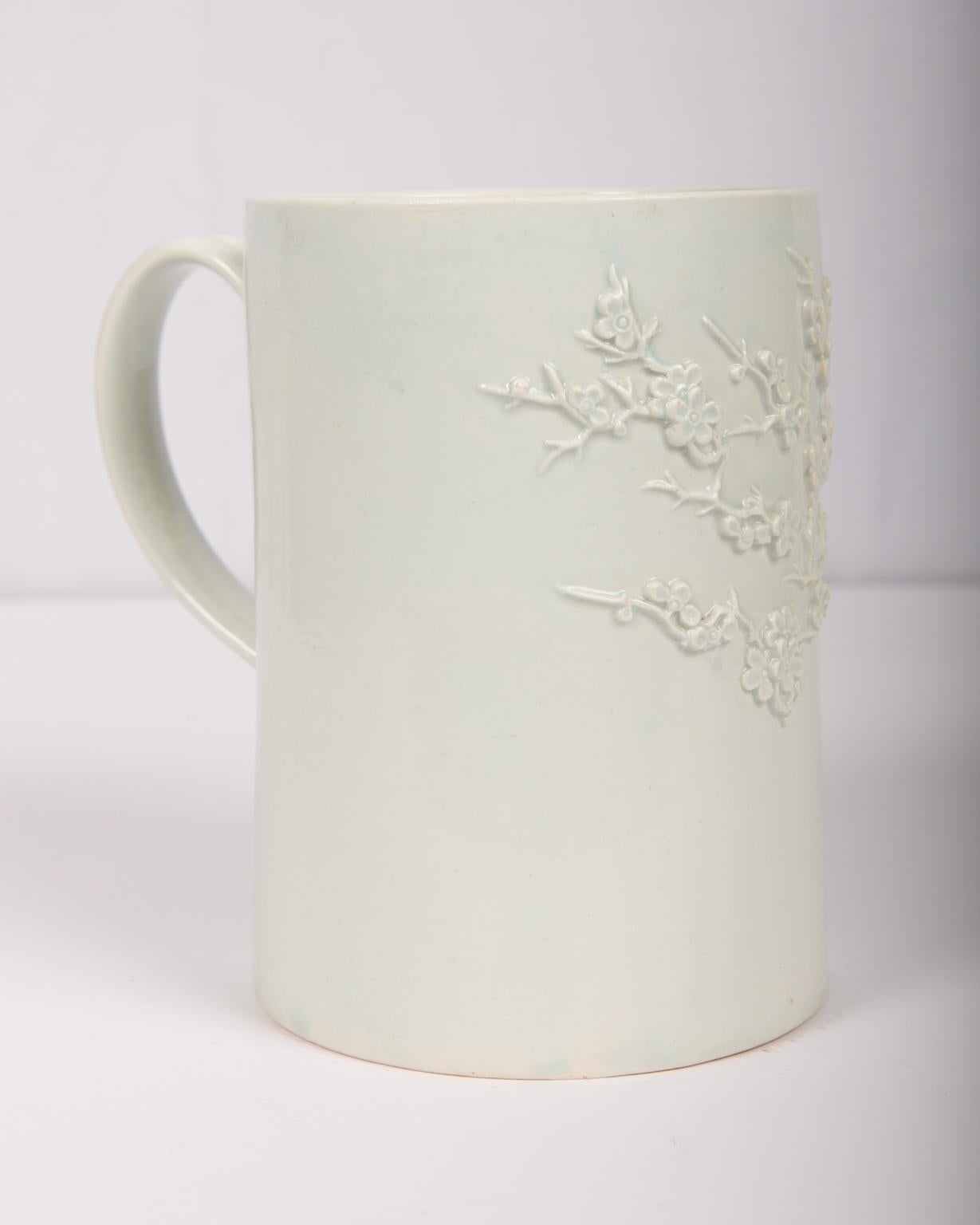 A tall Bow Porcelain tankard dating from the mid-18th century, 1755-1758. It features a profusion of delicately modeled prunus flower sprigs on the exterior. Though the mug is completely white, these flowers stand out beautifully because they are