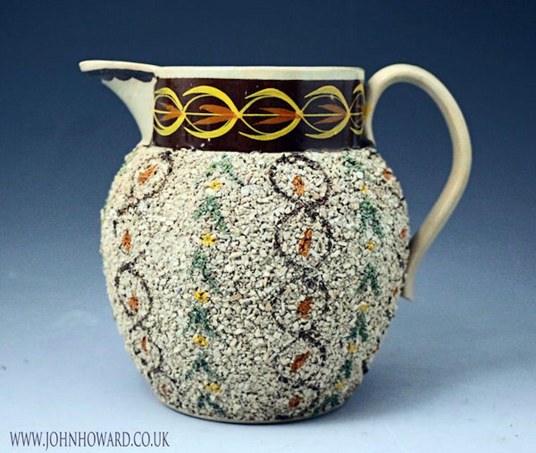 A rare and decorative antique pottery gravelware pitcher decorated in Prattware colors, early 19th century Staffordshire or Yorkshire.
    