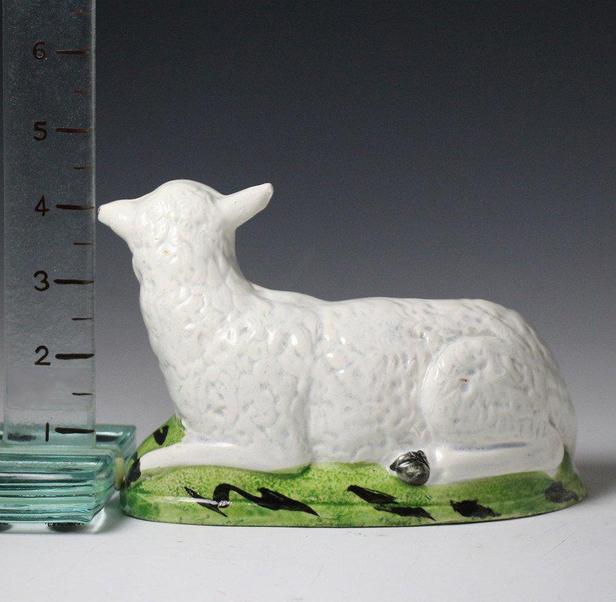 A fine pottery hollow based figure of a recumbent ewe on a green base. 
This naive figure has an engaging folk charm.