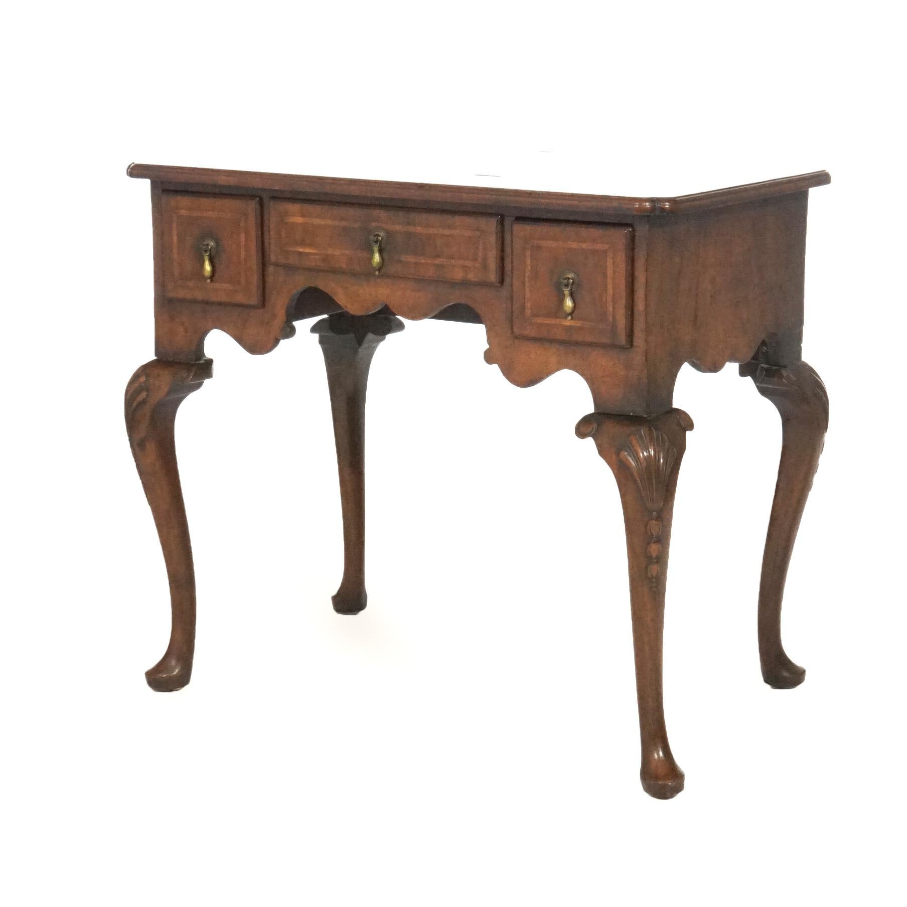 An antique English Queen Anne low boy offers mahogany construction with shaped top over case having three drawers, raised on cabriole legs with shell carved knees and terminating in pad feet, satinwood inlaid banding throughout, 18th