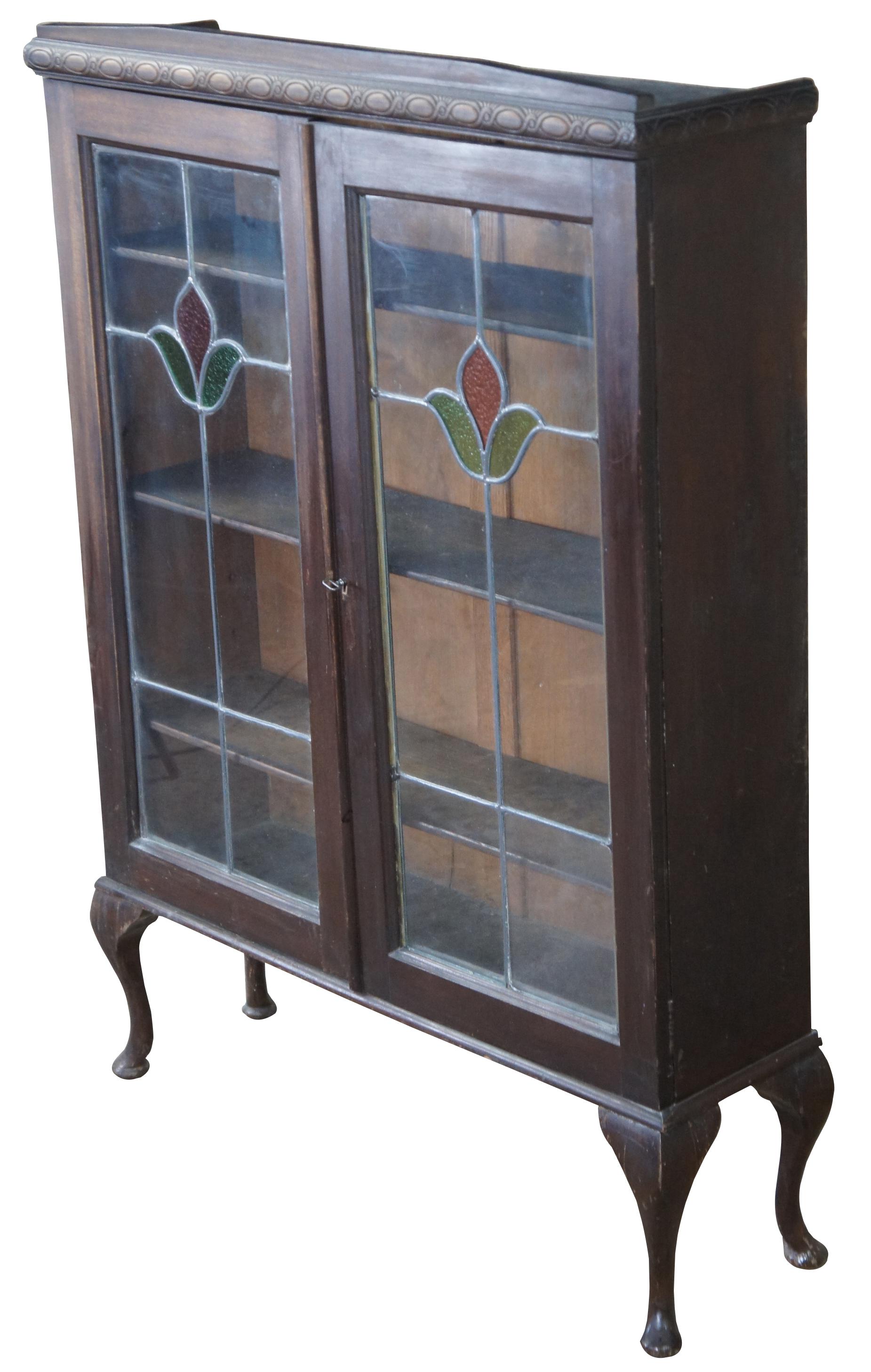 Antique English leaded glass curio cabinet or bookcase featuring Queen Ann styling with a rose or flower slag glass insert and cabriole legs. Measures: 53