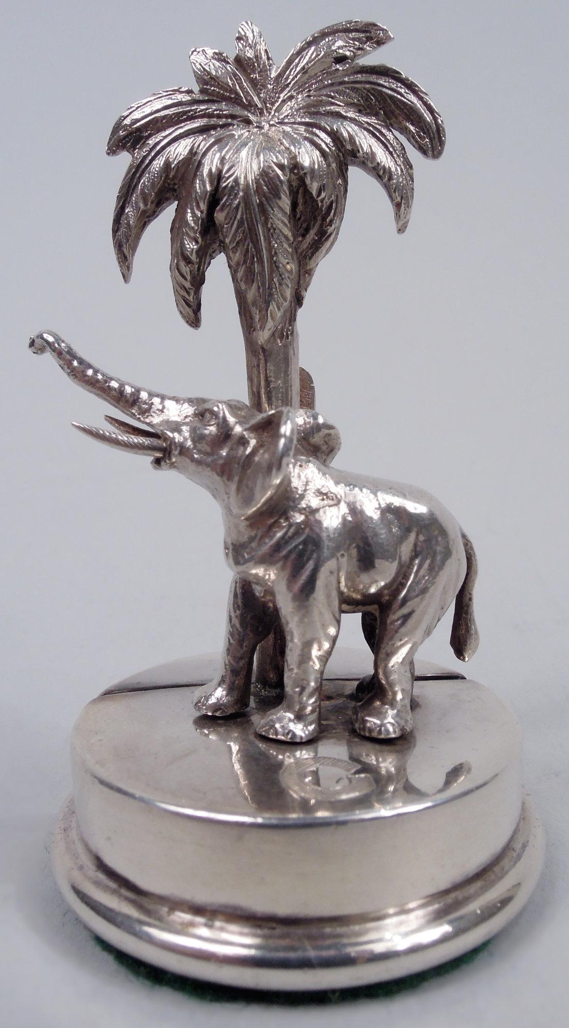 Set of 4 George V sterling silver place card holders. Made by Goldsmiths & Silversmiths in London in 1913. Each: An elephant with raised trunk and sharp tusks stands next to a palm tree. A cast group with back post clip mounted to round base.