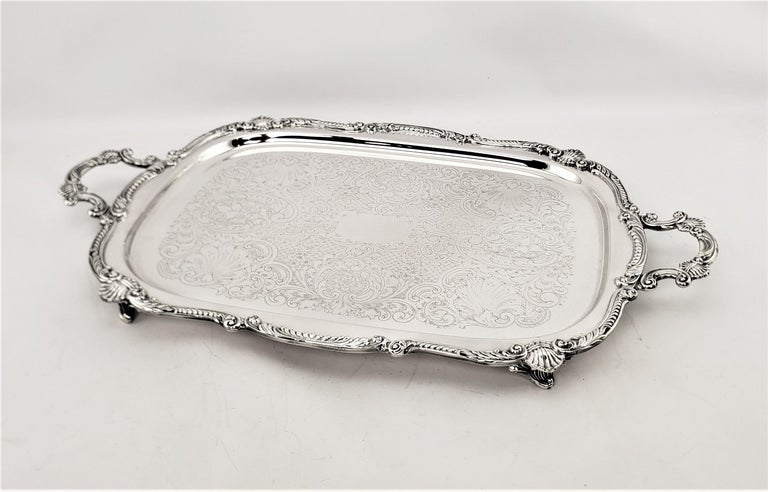 This silver plated serving tray is hallmarked by an unknown English maker, and presumed to date to approximately 1920 and done in a Victrian style. The tray is decorated with stylized shells and scrolls around the outside edges, which is replicated
