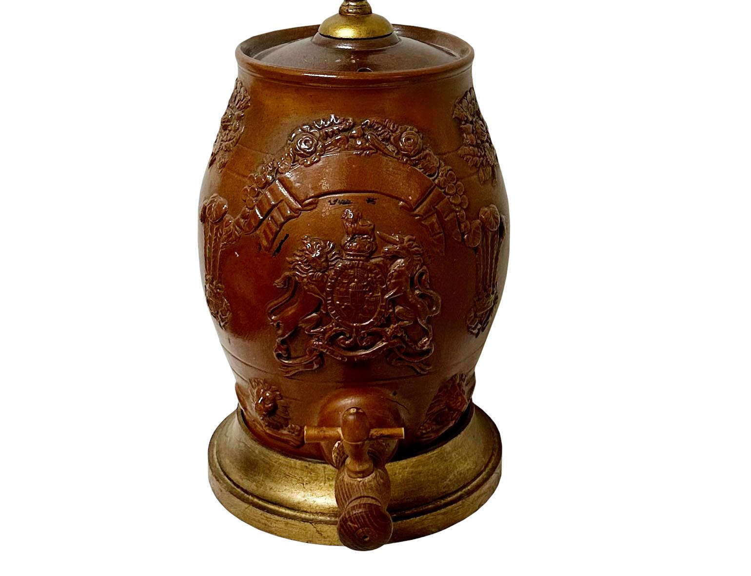 A 19th century English Redware jug made into a lamp with its wooden spigot and custom gold gilt wooden base.