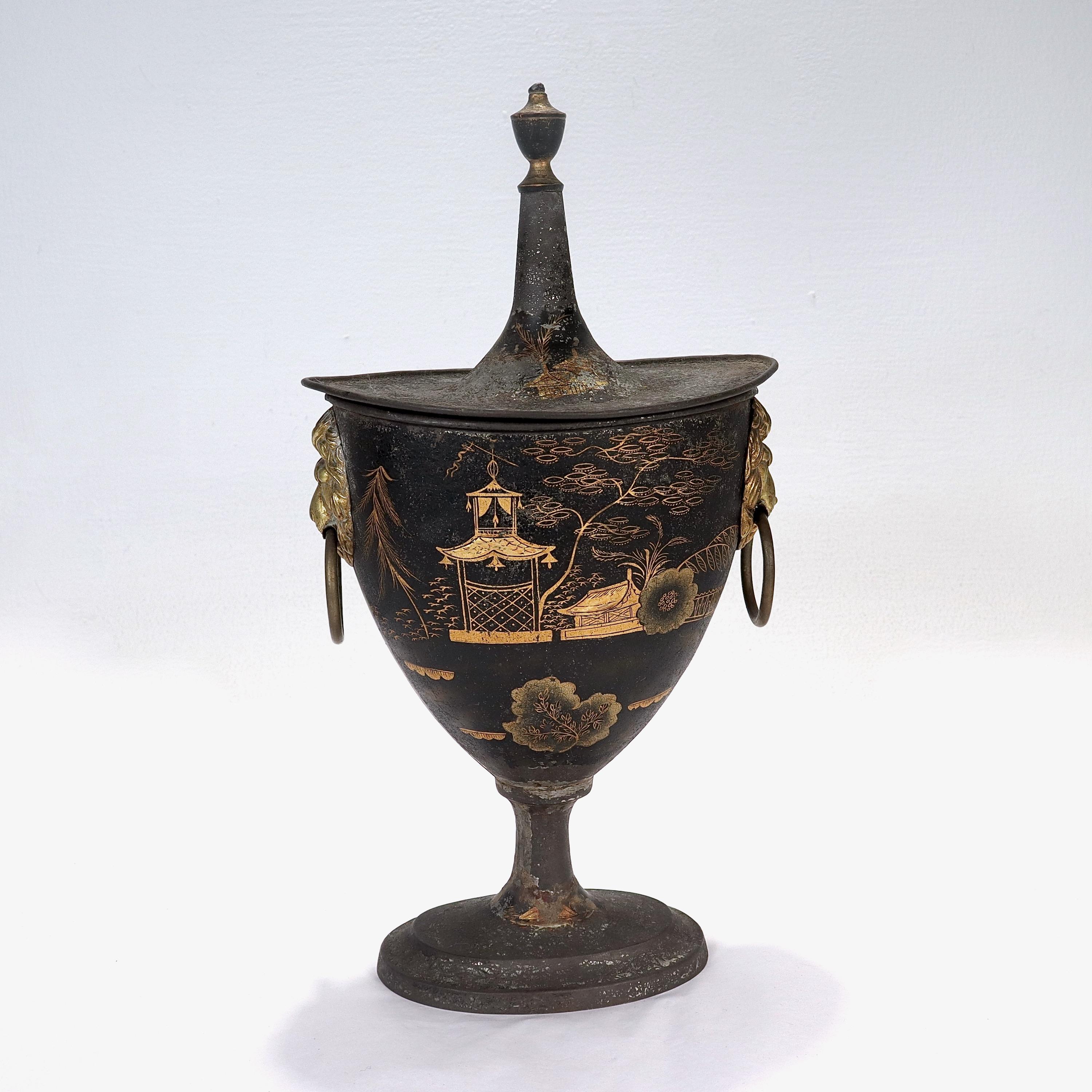 A fine antique toleware covered urn or vase.

Decorated throughout with gilt Chinoiserie decoration.

There is a figural lion's heads to the left & right sides each with a ring handle in their mouth.

There is noticeable loss throughout to the