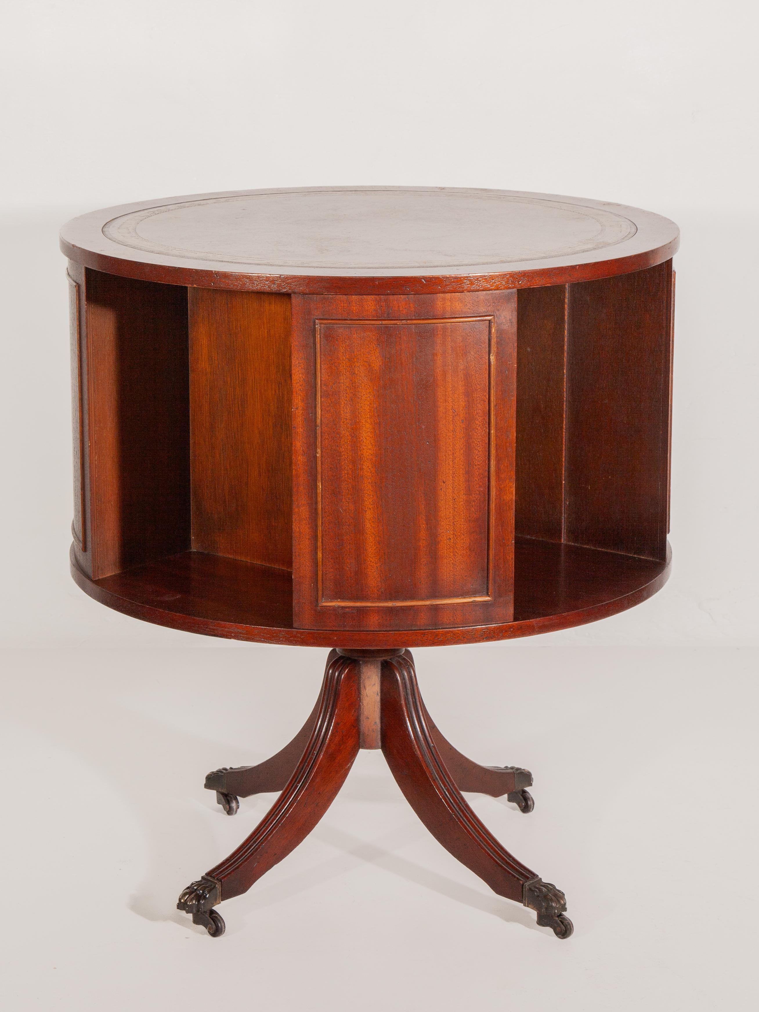 Antique 19th Century English Regency revolving Drum Table. Table features brown leather inlay top and four doors. The doors are positioned around the table's circumference and provide ample storage space for books or bottles while maintaining the