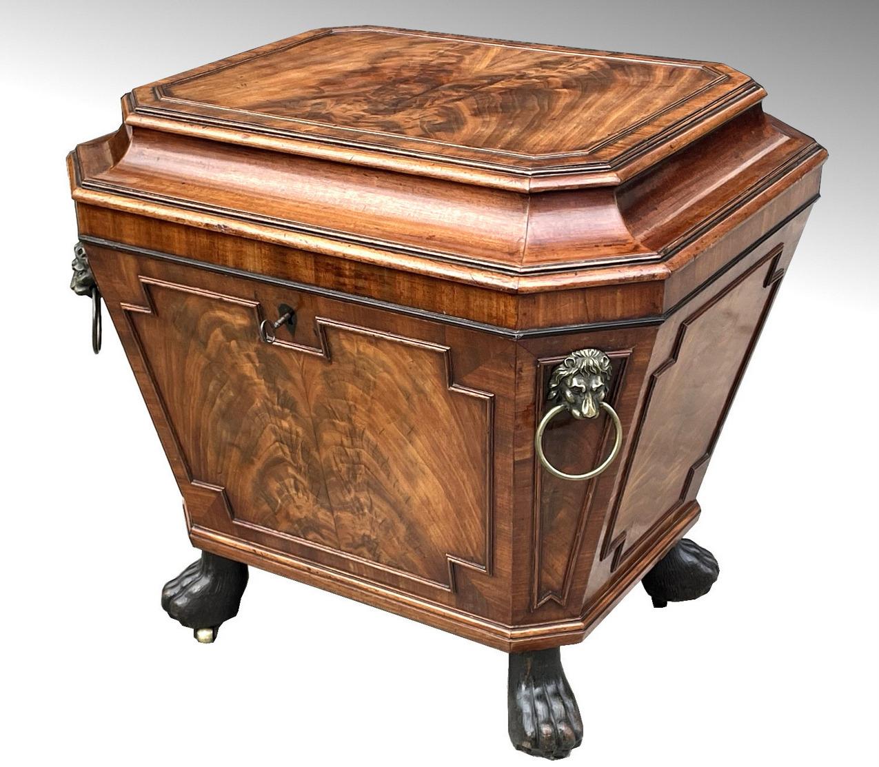 Superb Flame Mahogany Wine Cellarette of sarcophagus outline and of English origin. First quarter of the 19th century, Regency period. 

The flat top lid opening to reveal the interior with its original lead lining and stopper, each upper corner