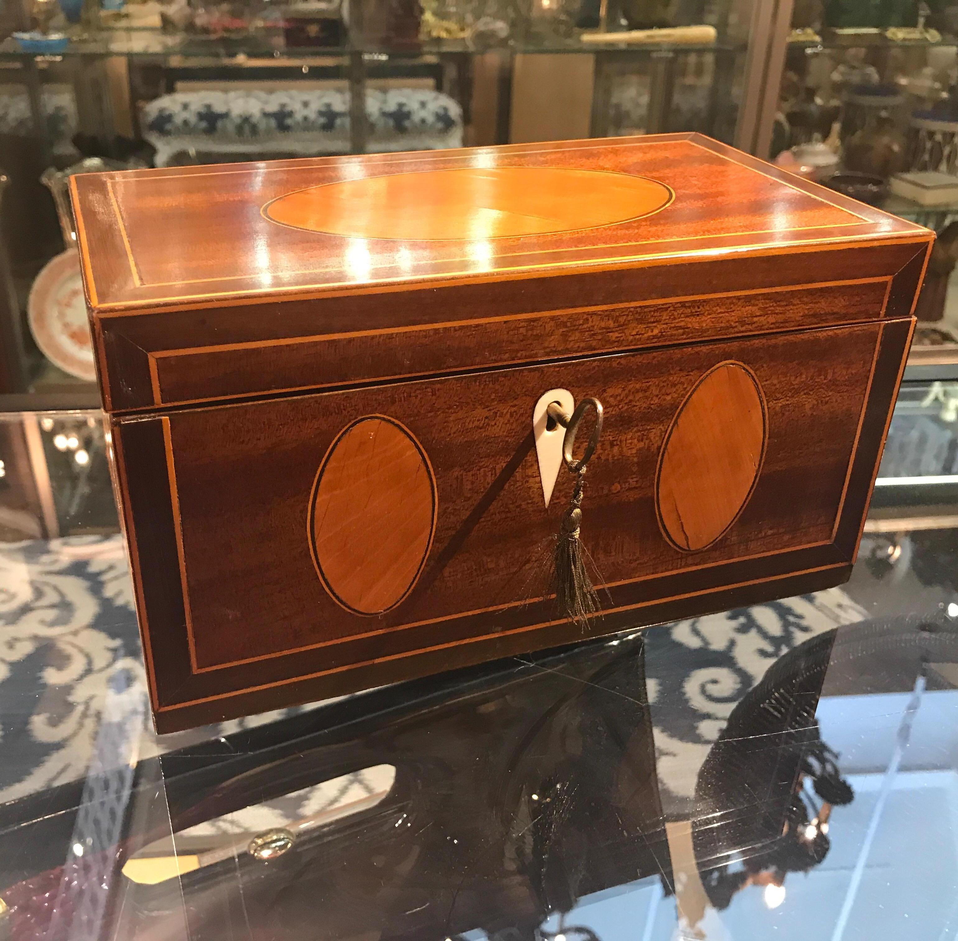 Pure elegance in mahogany and satinwood. This Regency style locking box with mahogany background with oval panels and hand inlaid stainwood with delicate ebony string inlay accent. The oval panes are a sign of a very skilled cabinetmaker. The paper