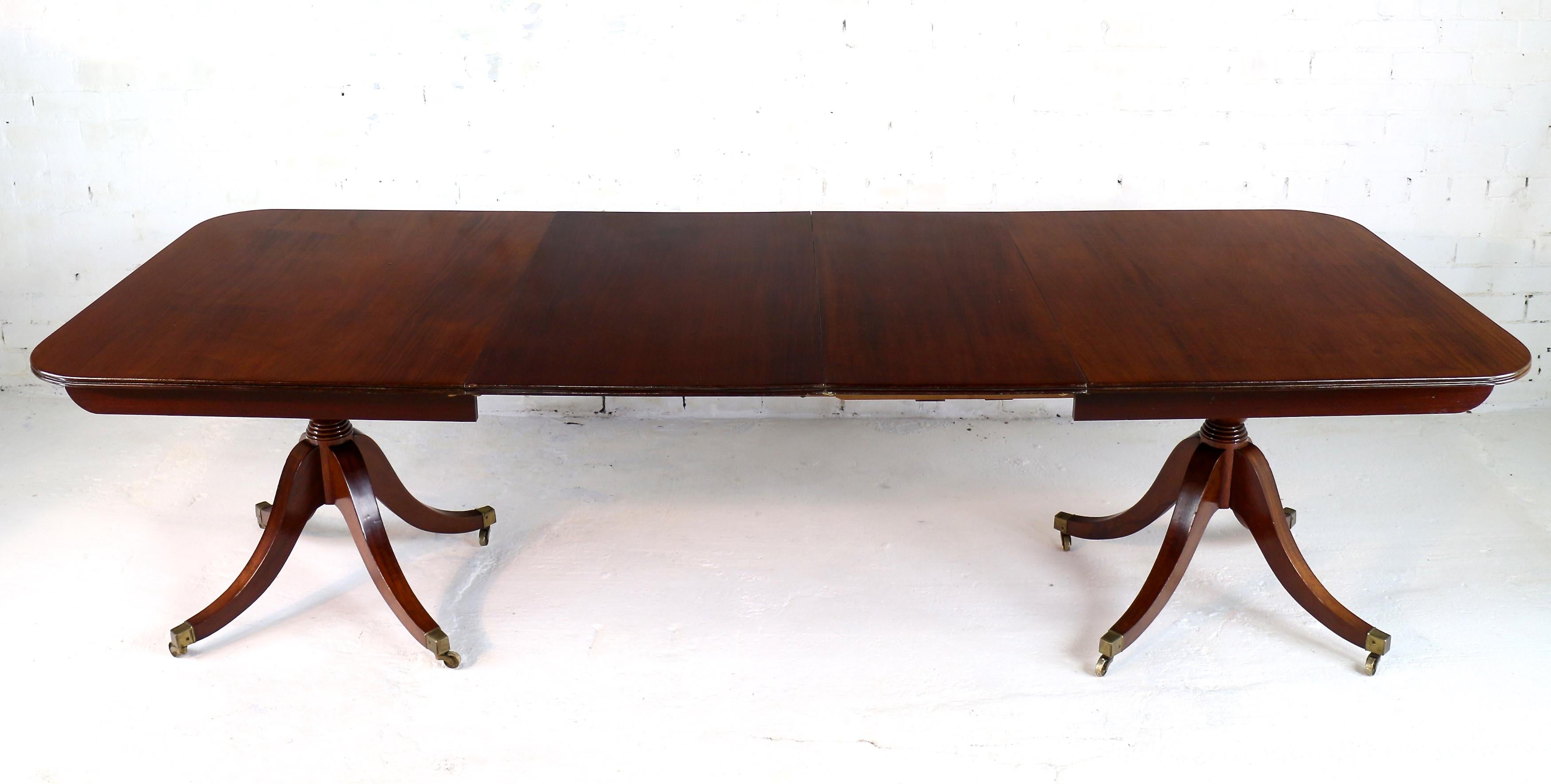 An elegant and well proportioned Regency & later English mahogany twin pedestal extending dining table with two additional leaves. This handsome table features an original early 19th century solid mahogany top with a reeded edge supported on early