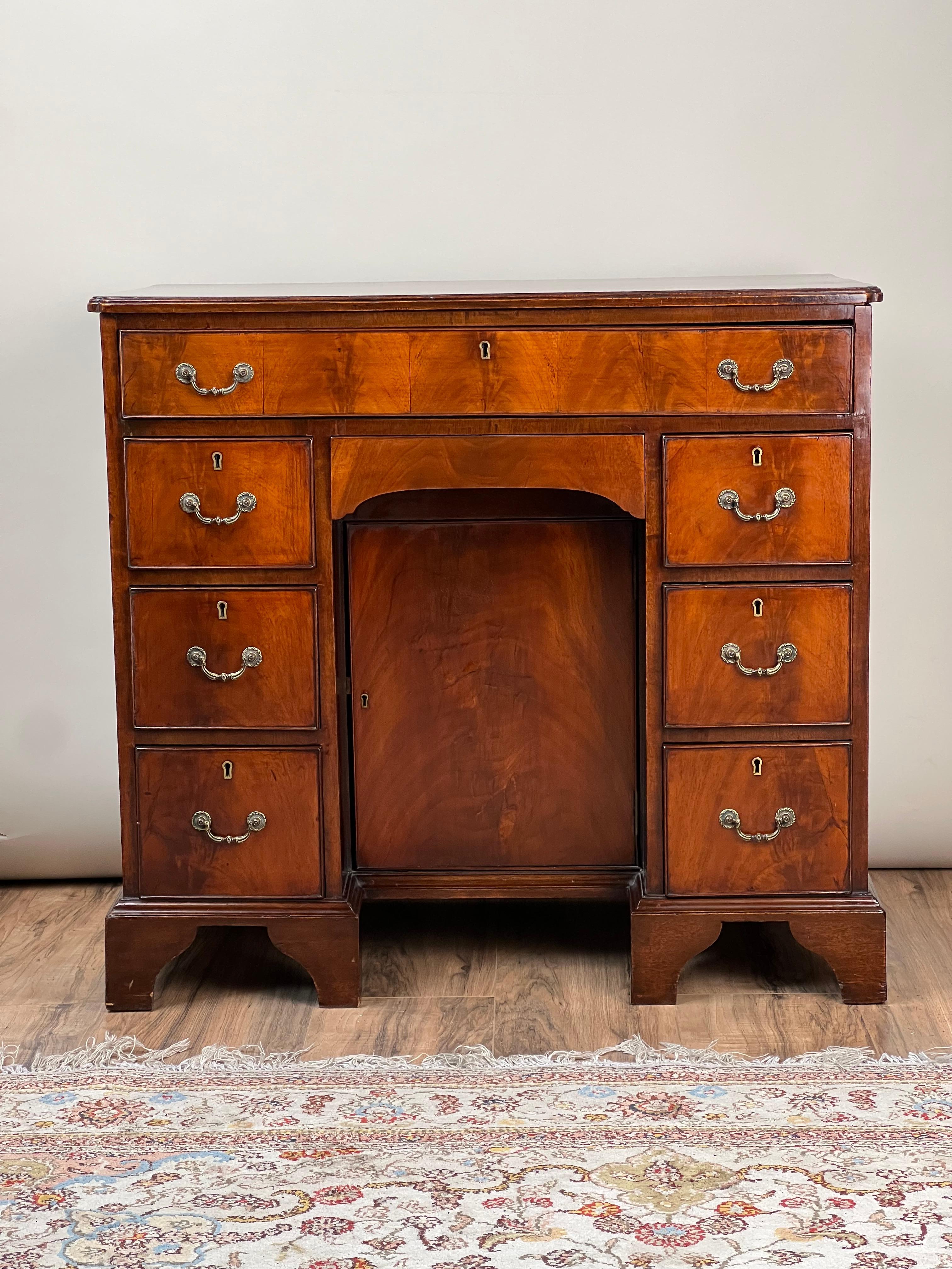 Questa antica scrivania inglese Regency in mogano con foro al ginocchio, risalente al 1820 circa, è un esempio straordinario dei mobili eleganti e funzionali del periodo Regency. La sua ricca impiallacciatura in mogano ha sviluppato una bella patina
