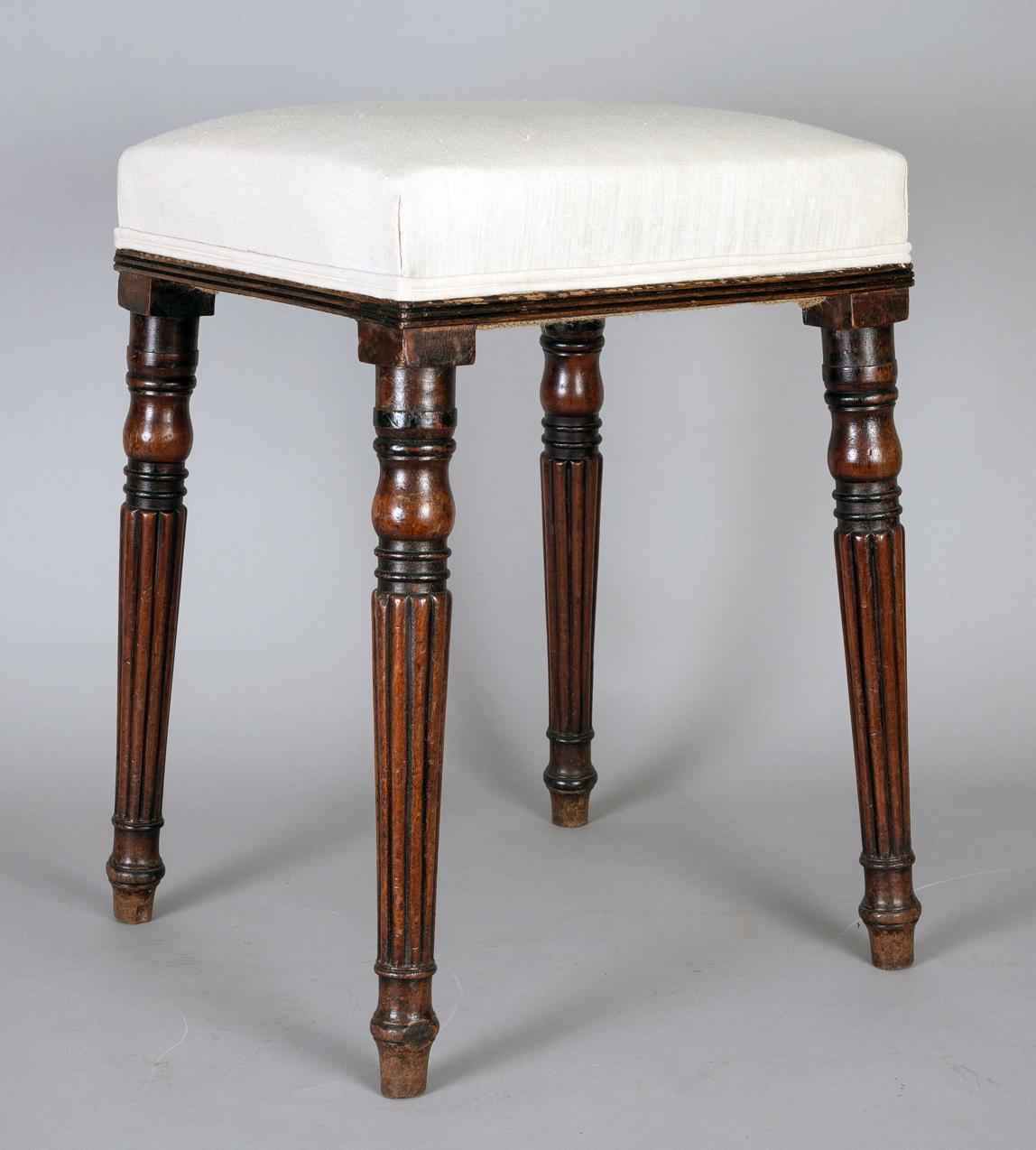 Regency mahogany stool with slender reeded and turned legs. Upholstered in an off-white linen fabric.