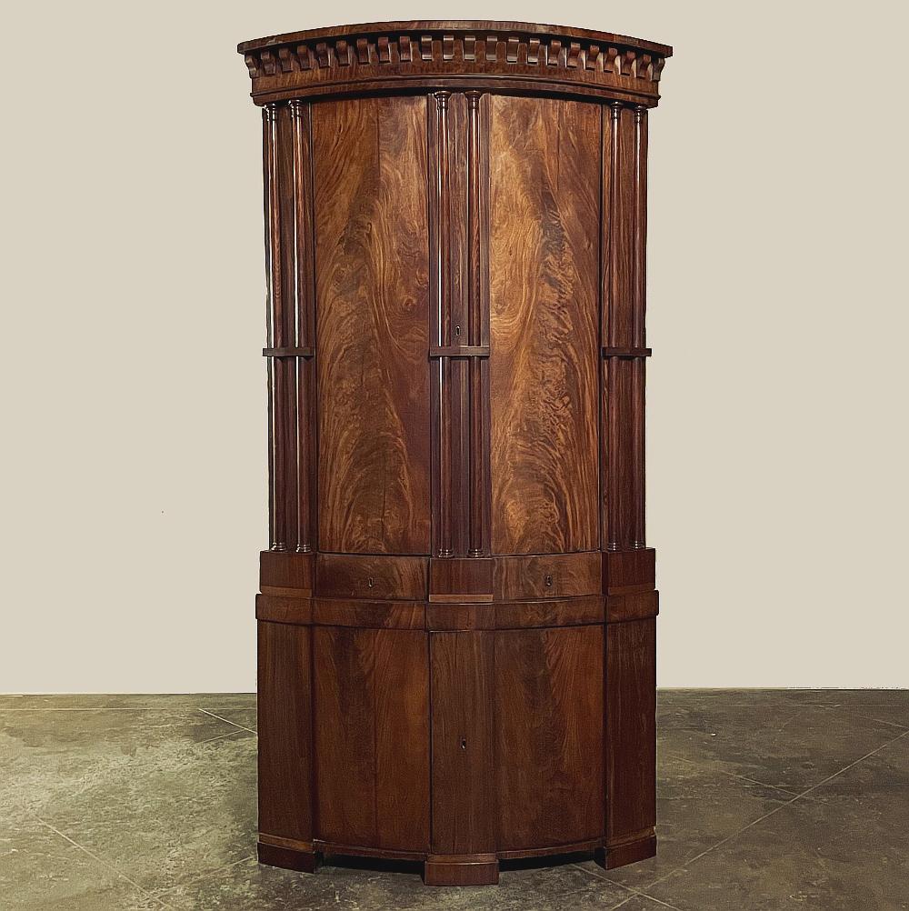 Constructed on a great scale in the Neoclassical style, this English Regency Period Grand Corner Cabinet is a clever solution for corner storage. The cabinet opens to reveal two separate shelved interiors separated by two small drawers. When closed,