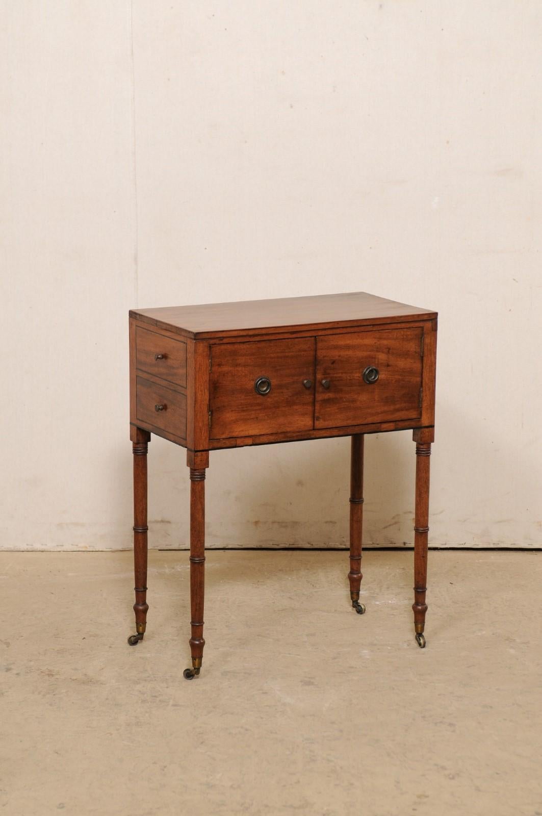 An English Regency side chest from the early 20th century. This antique side chest/end table from England features a rectangular-shaped case with pair of doors along one long side, which open to reveal hidden storage within, and each short end