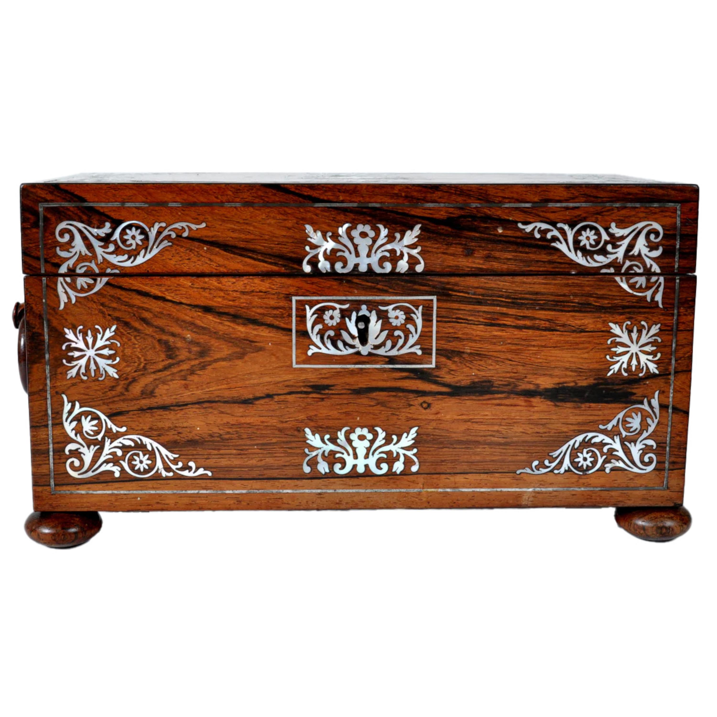 A fine quality antique English Georgian Regency inlaid rosewood tea Caddy, circa 1820. 
The caddy is made from the  hinged lid is finely inlaid with mother of pearl, and the base with corresponding floral inlay, the sides fitted ring handles. The