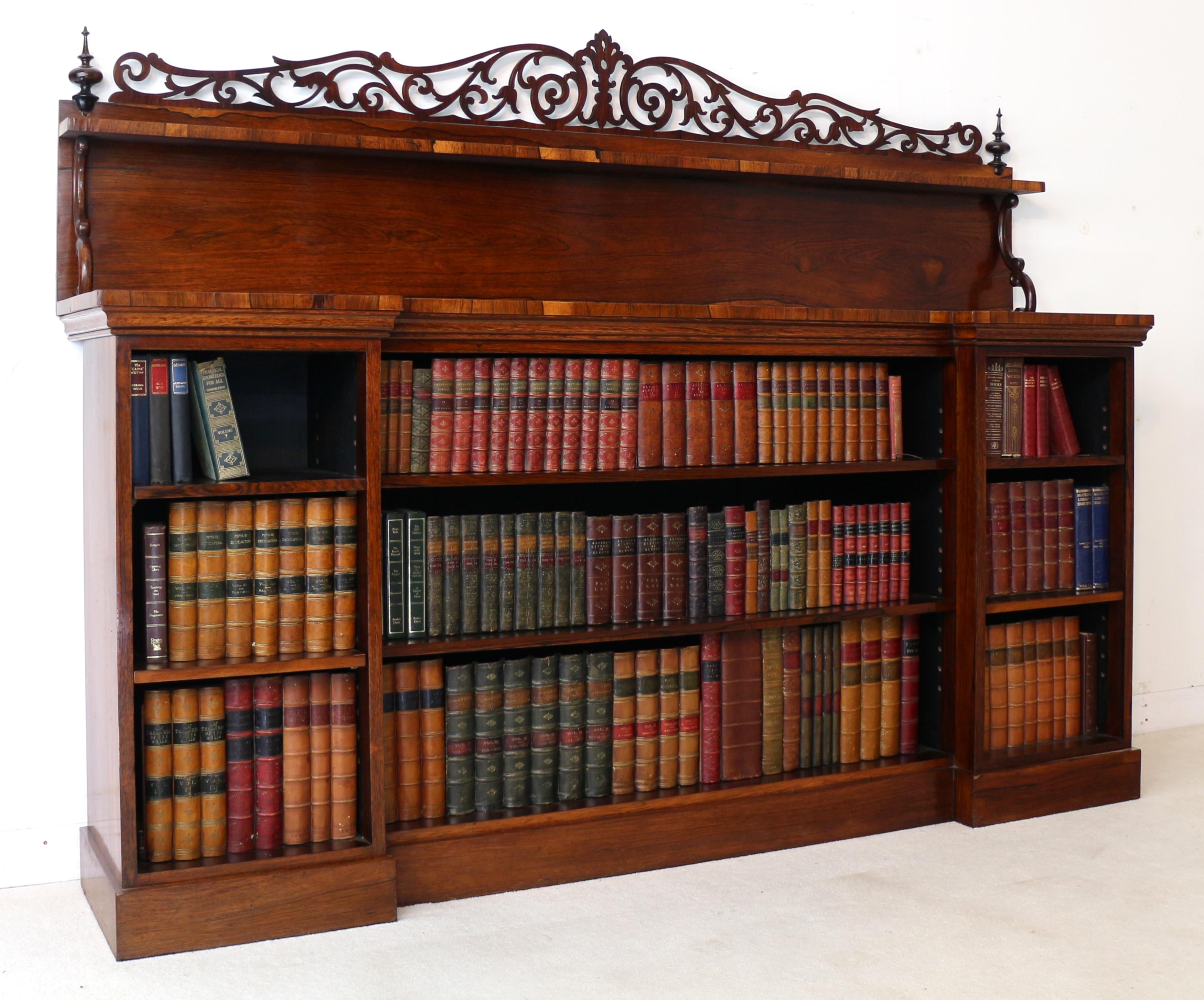 A superb quality Indian Regency rosewood inverted breakfront bookcase dating to circa 1820. With a stunning pierced scrolling fretwork back with turned finials above a shelf supported by C-scroll supports, the inverted breakfront top above an open