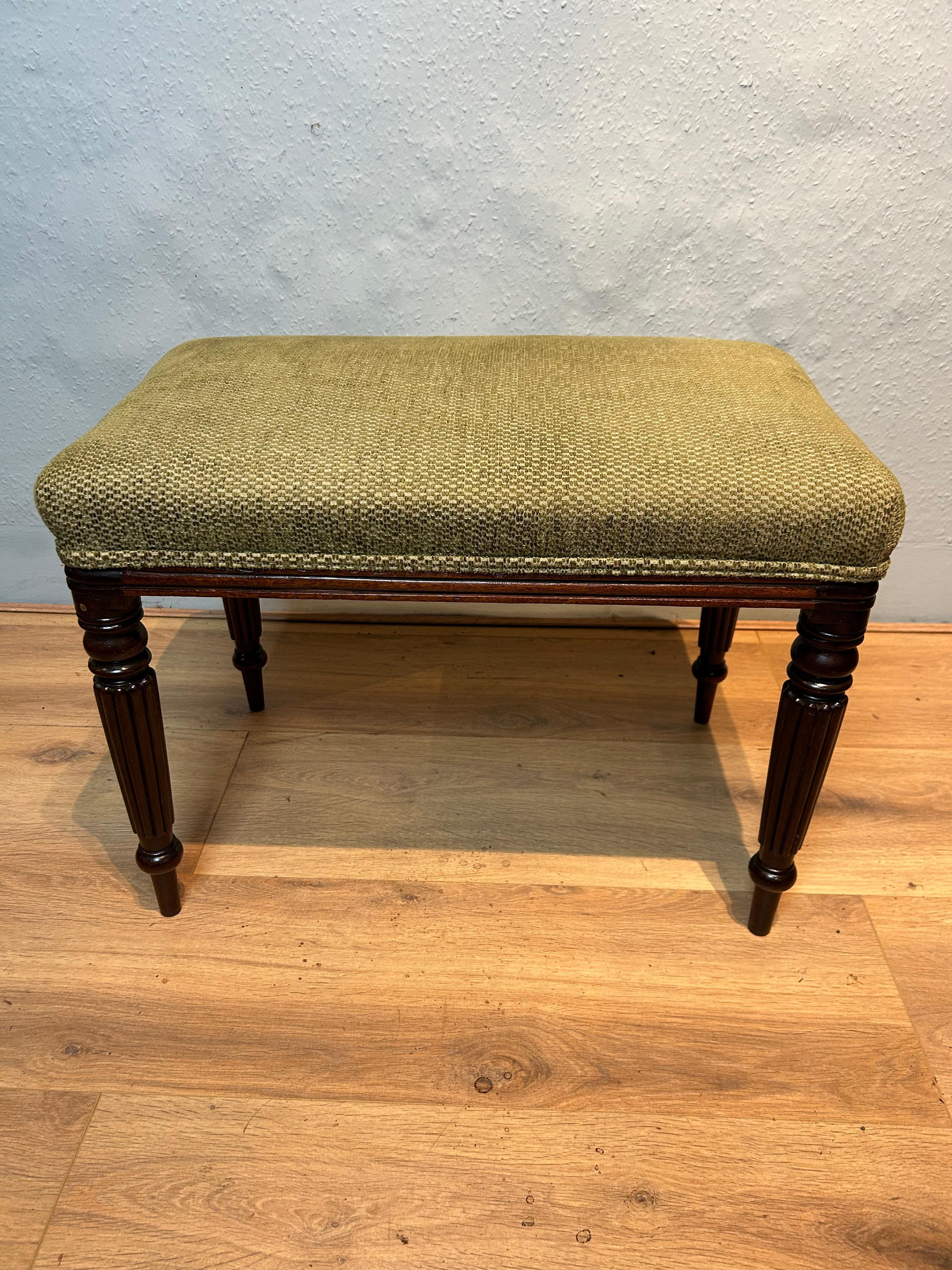 English Regency mahogany stool in the manner of Gillows of Lancaster circa 1820, fully upholstered with a moulded frieze resting on finely tuned reeded legs.