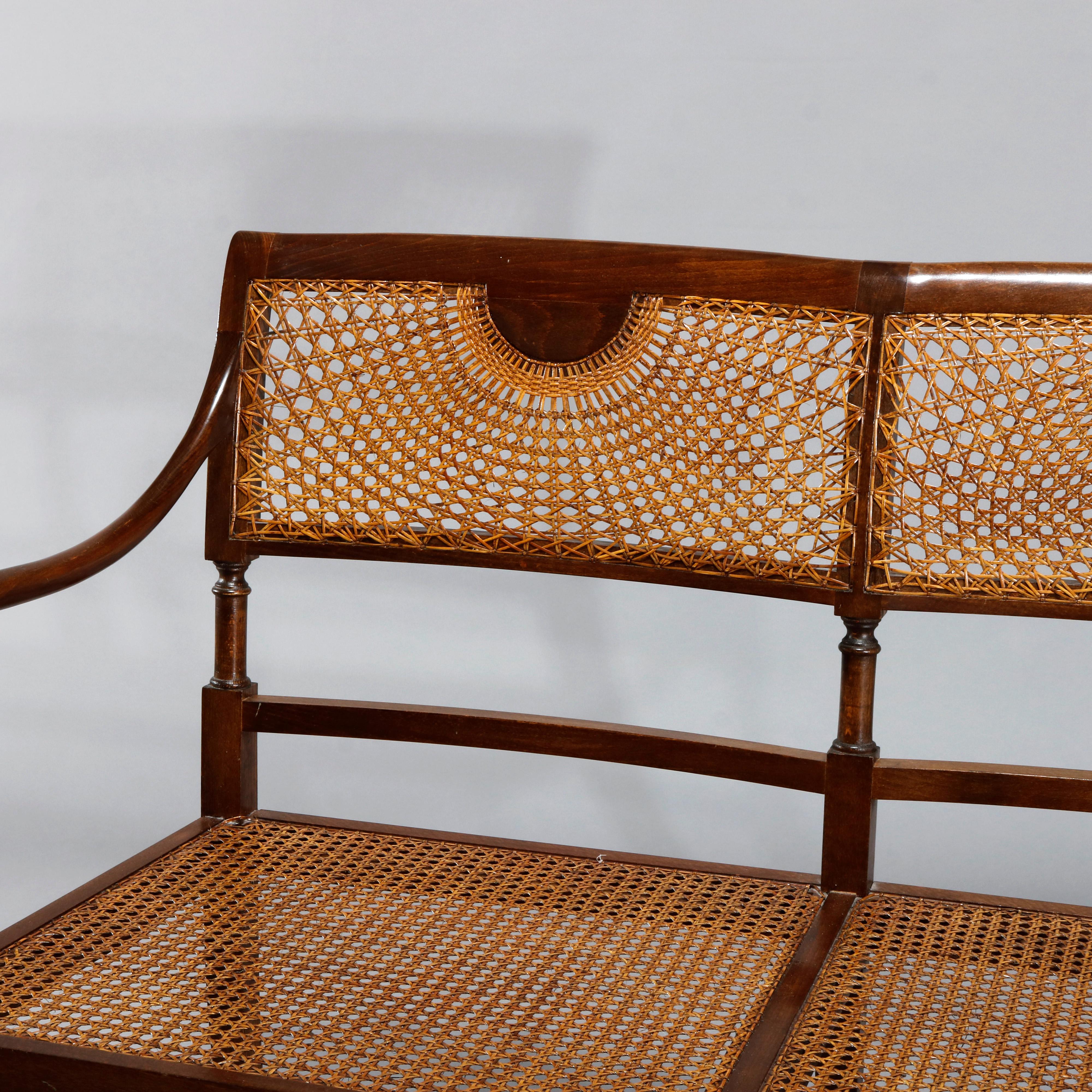 An antique English Regency style settee offers mahogany frames with backs having sunburst pressed cane backs, caned seats, and has cushion as photographed, c1930

Measures: 33