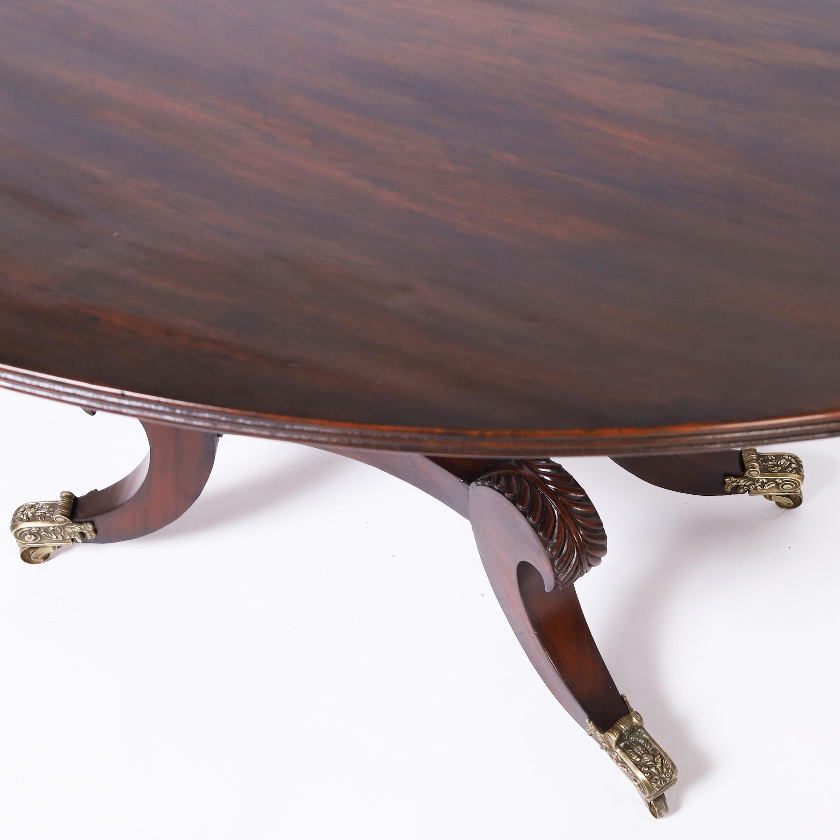 Impressionnante table de petit déjeuner ou de salle à manger de style Régence anglaise du XIXe siècle, fabriquée à la main en acajou, avec un plateau ovale à bord perlé sur un piédestal reposant sur une plate-forme à quatre pieds sabres stylisés
