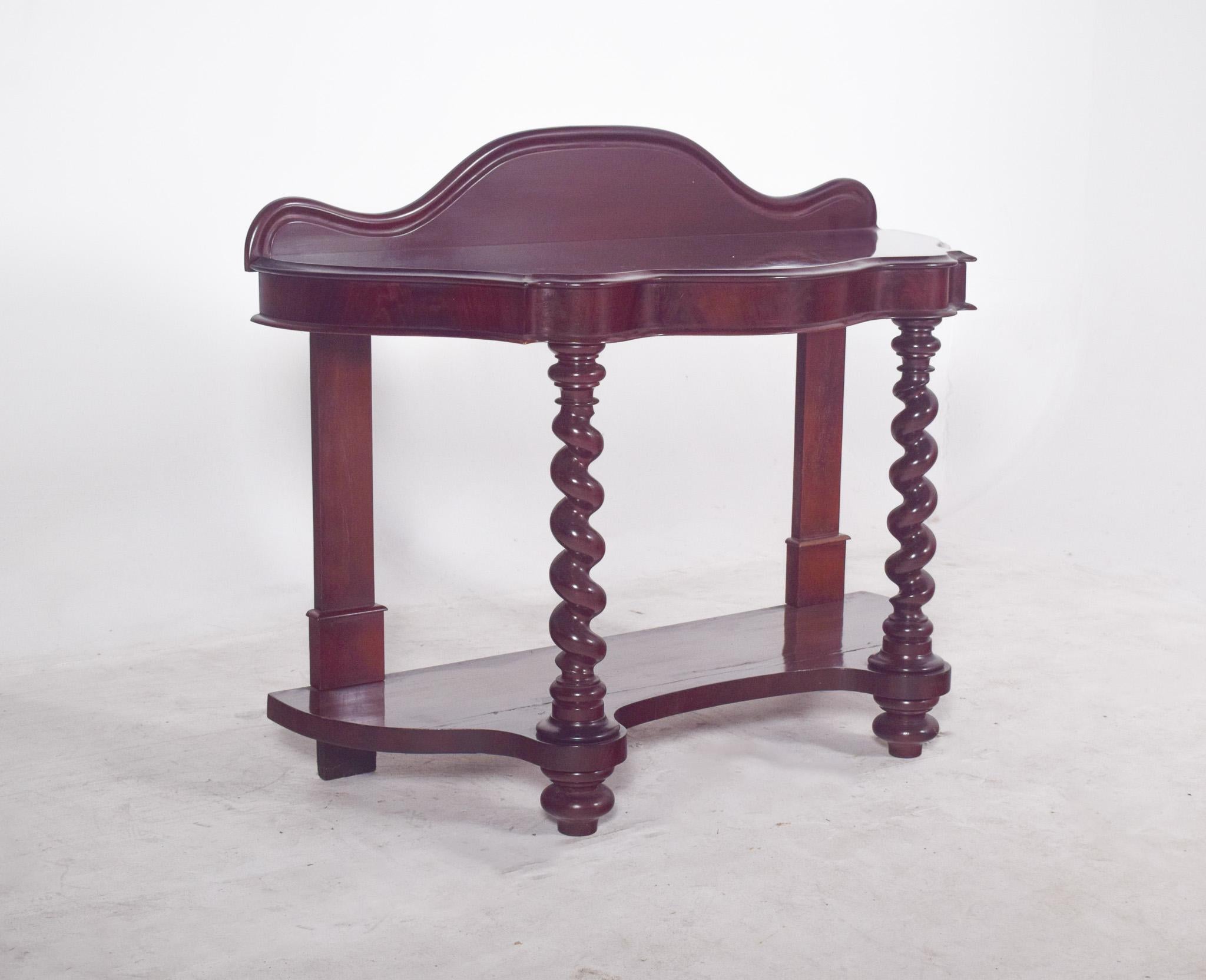 Romantic console in mahogany. The top has a wavy design, with a raised cut-out at the back, suggesting inspiration for decorative hall or living room furniture. The front structure is supported by two legs on twisted columns, which reinforce the