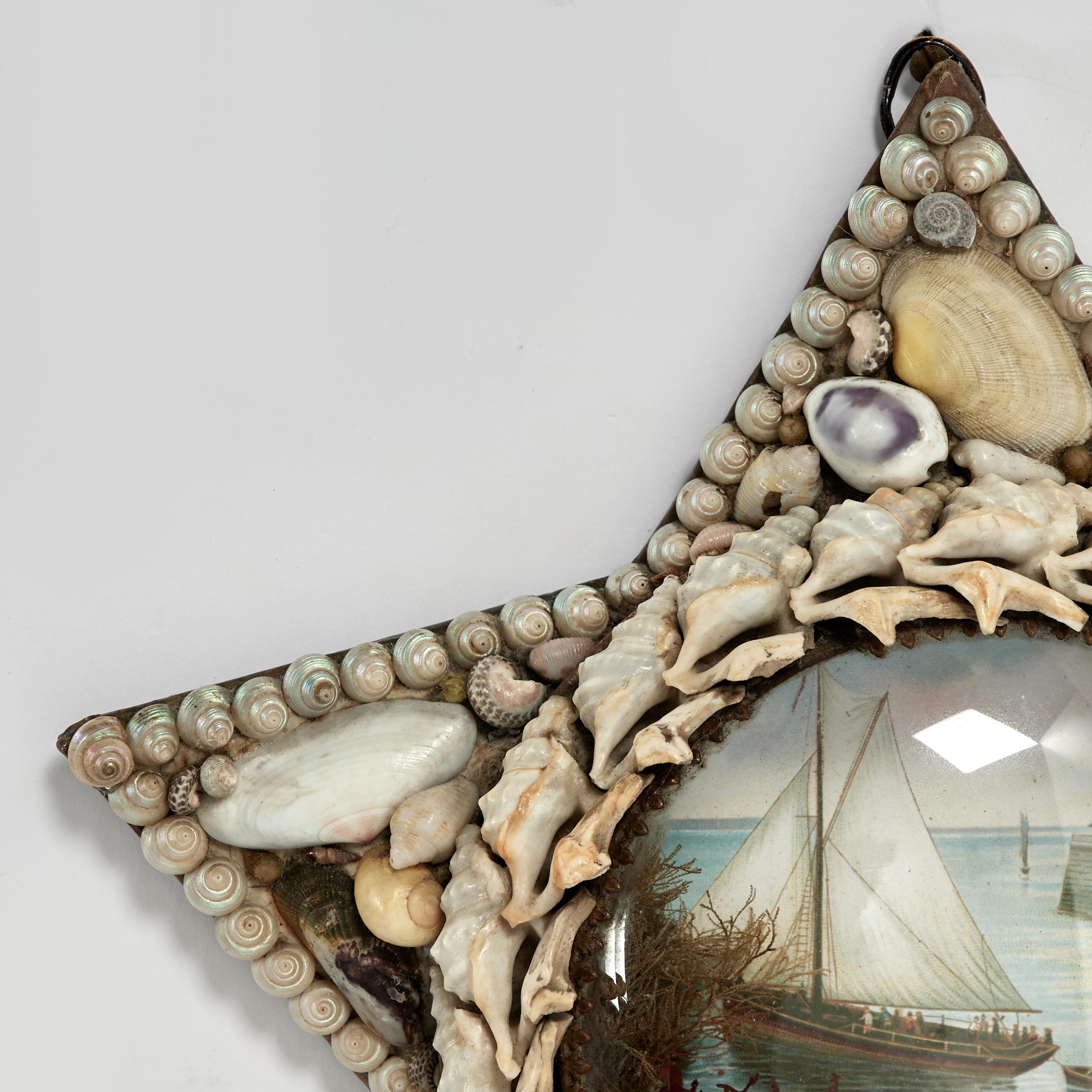 Handgefertigter Valentinsgruß für Seeleute aus der britischen Kolonialzeit in Form eines Sterns, der mit exotischen Muscheln um das Bild eines Segelboots im Hafen herum komponiert ist, das durch eine konvexe Glaslinse gesehen wird. 