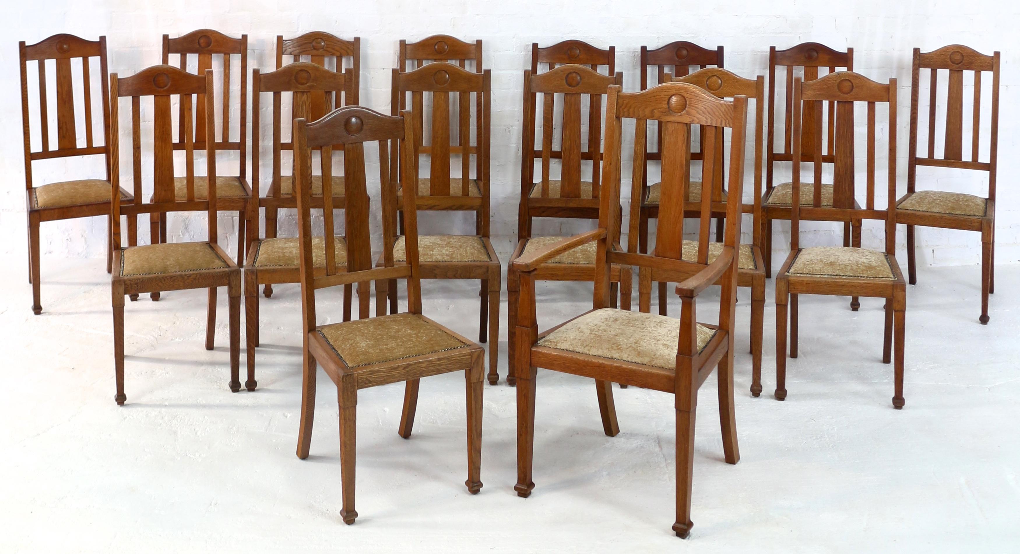 A rare set of sixteen good Arts & Crafts oak high back dining chairs by Shapland & Petter and dating to circa 1900. Comprising one carver armchair and fifteen side chairs, each with an arched top rail centered by an incised roundel and three