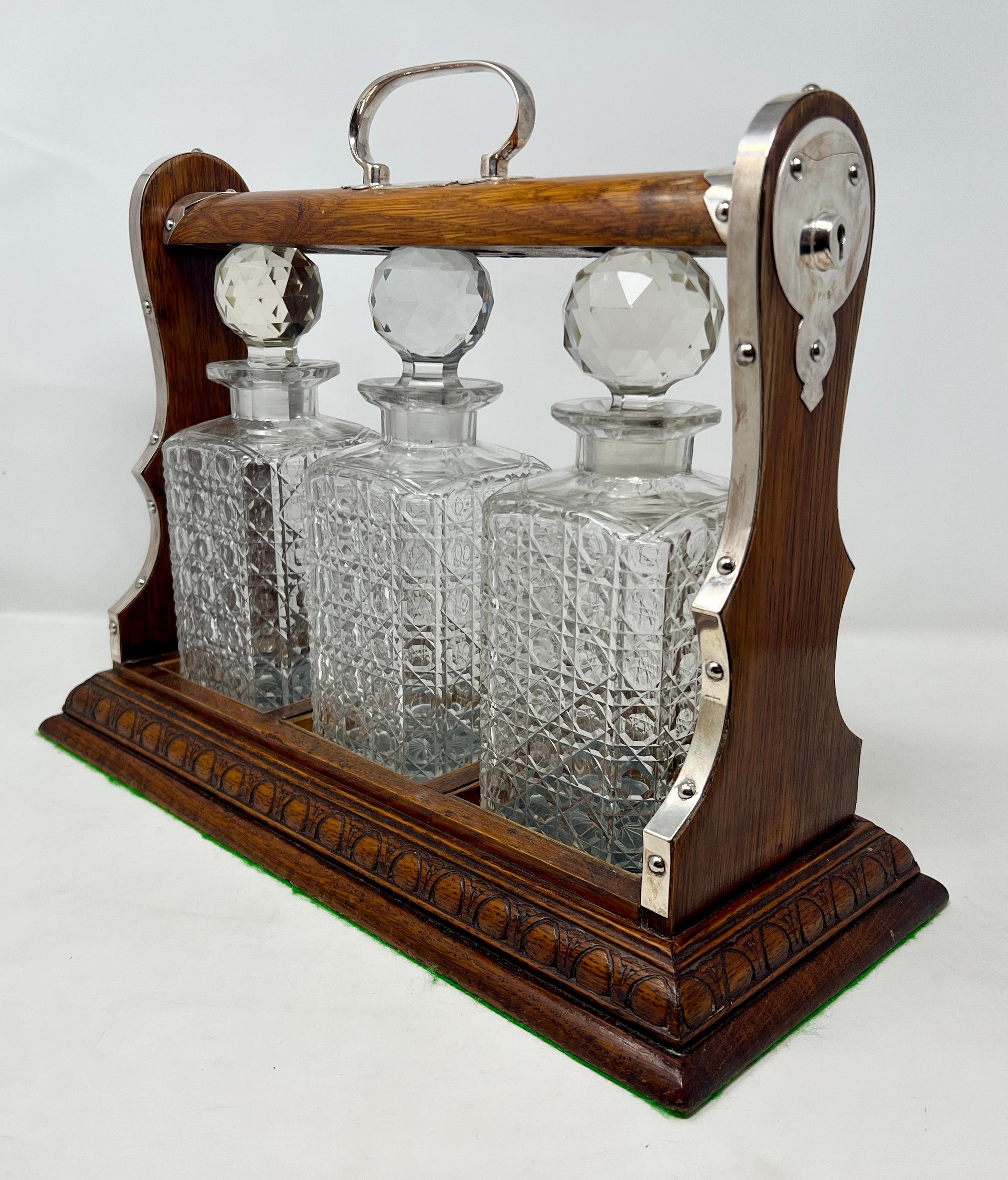 Antique English Golden Oak and Cut Crystal 3-Bottle Tantalus with Sheffield Silver Plated Mounts along with Lock and Working Key, Circa 1890.