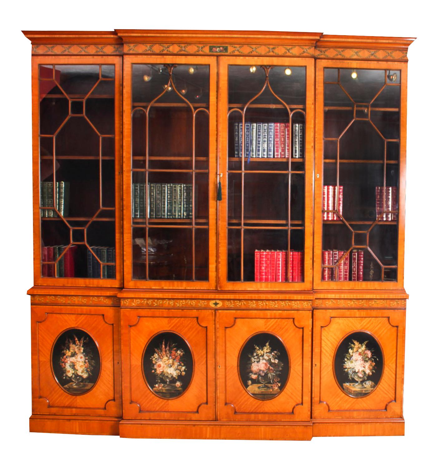 This is a beautiful antique Sheraton Revival top quality four door breakfront bookcase, masterfully crafted in rich satinwood, circa 1880 in date.

This magnificent bookcase features a frieze and cornice beautifully hand painted with scrolling