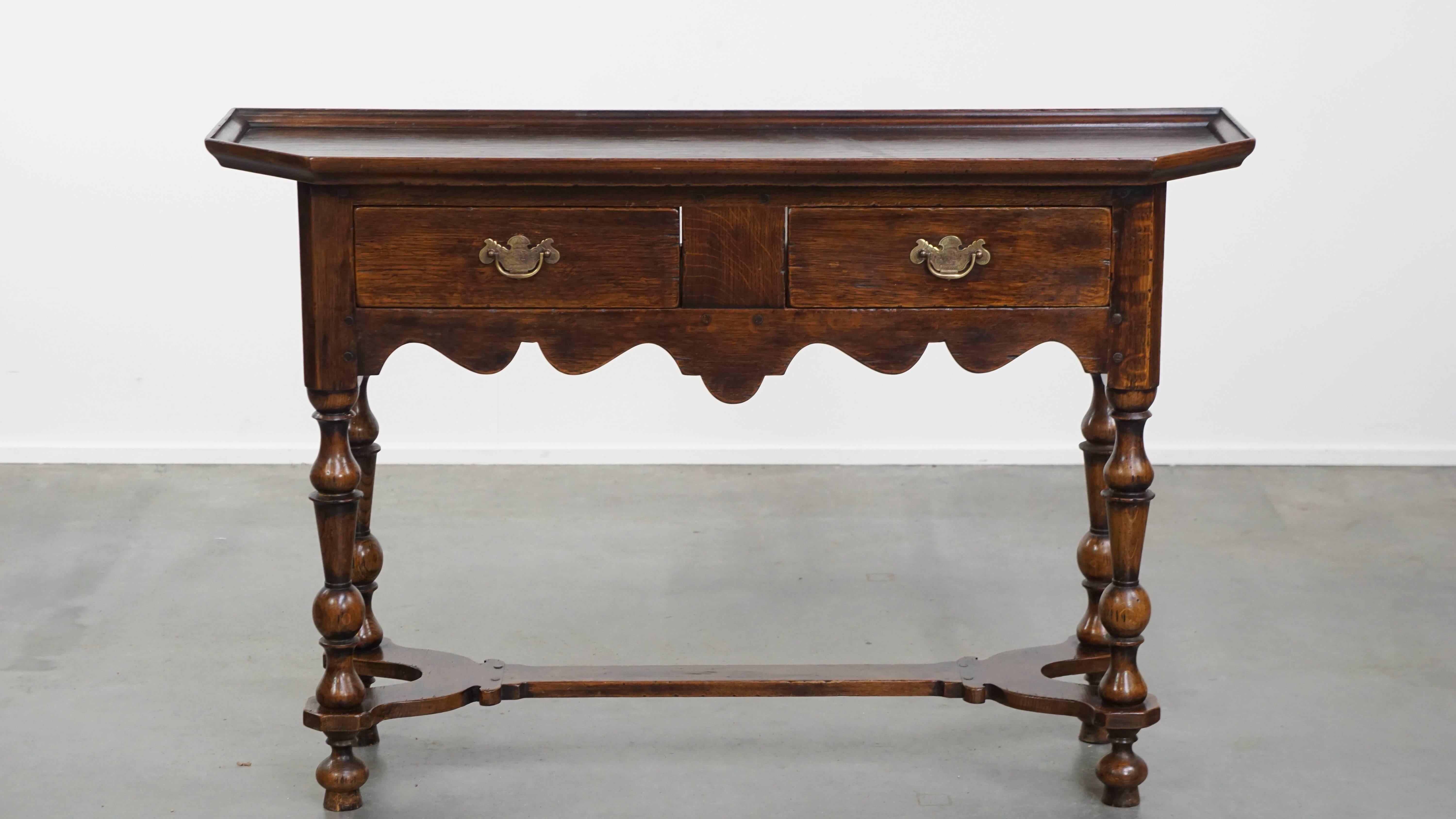Offered here this subtle, elegant and charming antique English side table / sideboard in oak with 2 drawers and decorative details.
This classic and refined antique English side table / sideboard fits beautifully into both modern and traditional