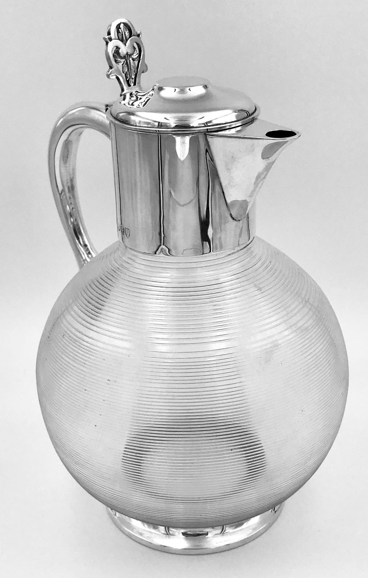 An unusual silver and glass English silver claret jug. The jug has a plain silver mount and a very unusual ribbed glass body.