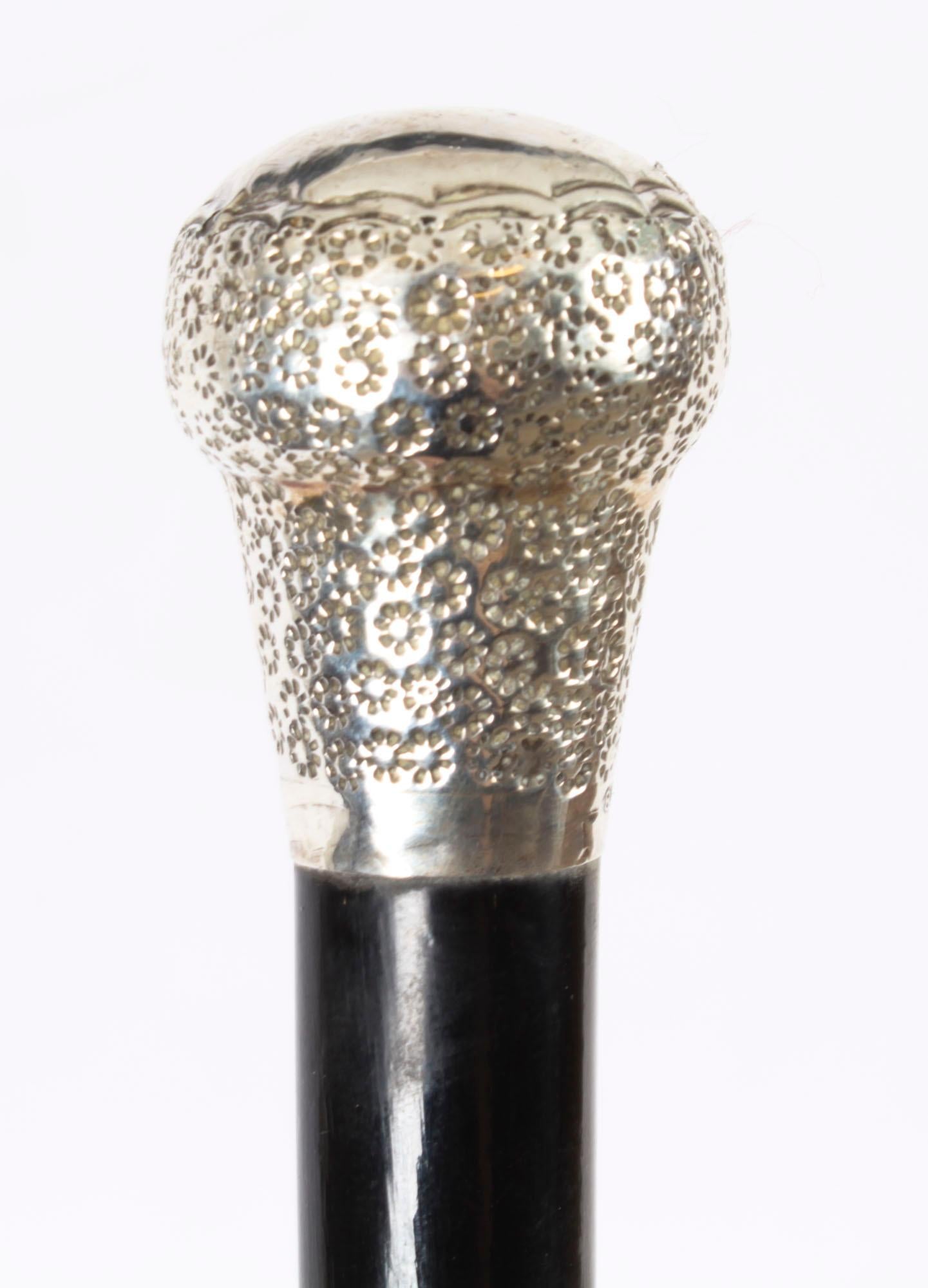 This is a beautiful antique sterling silver pommel walking stick bearing hallmarks for London,  dated 1883.

The striking stick features an ornate silver pommel having a profusely engraved circular flower like design and a vacant cartouche to top,