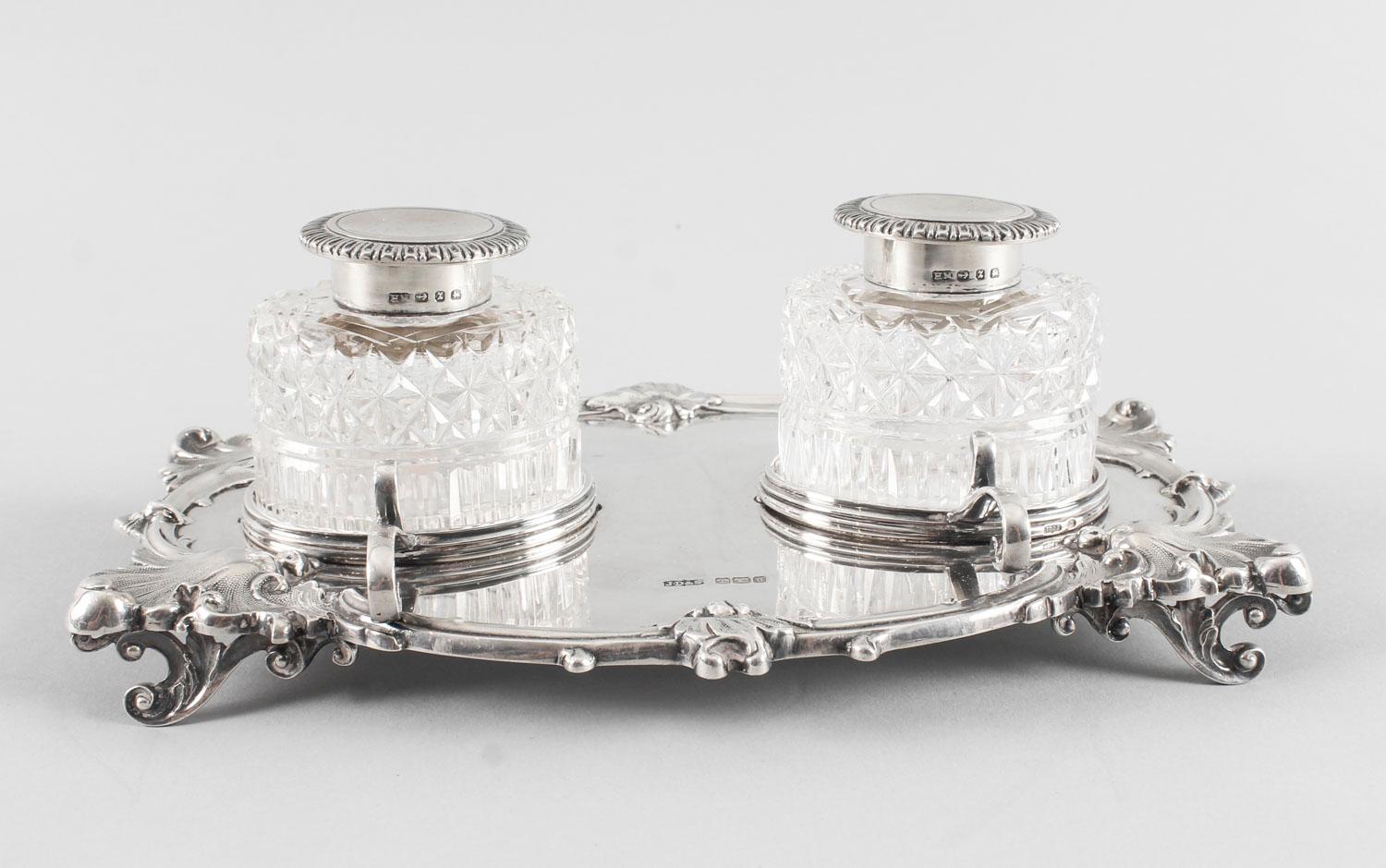 This is a wonderful antique sterling silver inkstand with hallmarks for Sheffield 1899 and the makers mark of James Dixon & Sons.

The shaped oval tray with leaf and scroll cast rim is raised on decorative scroll feet and supporting twin cut glass