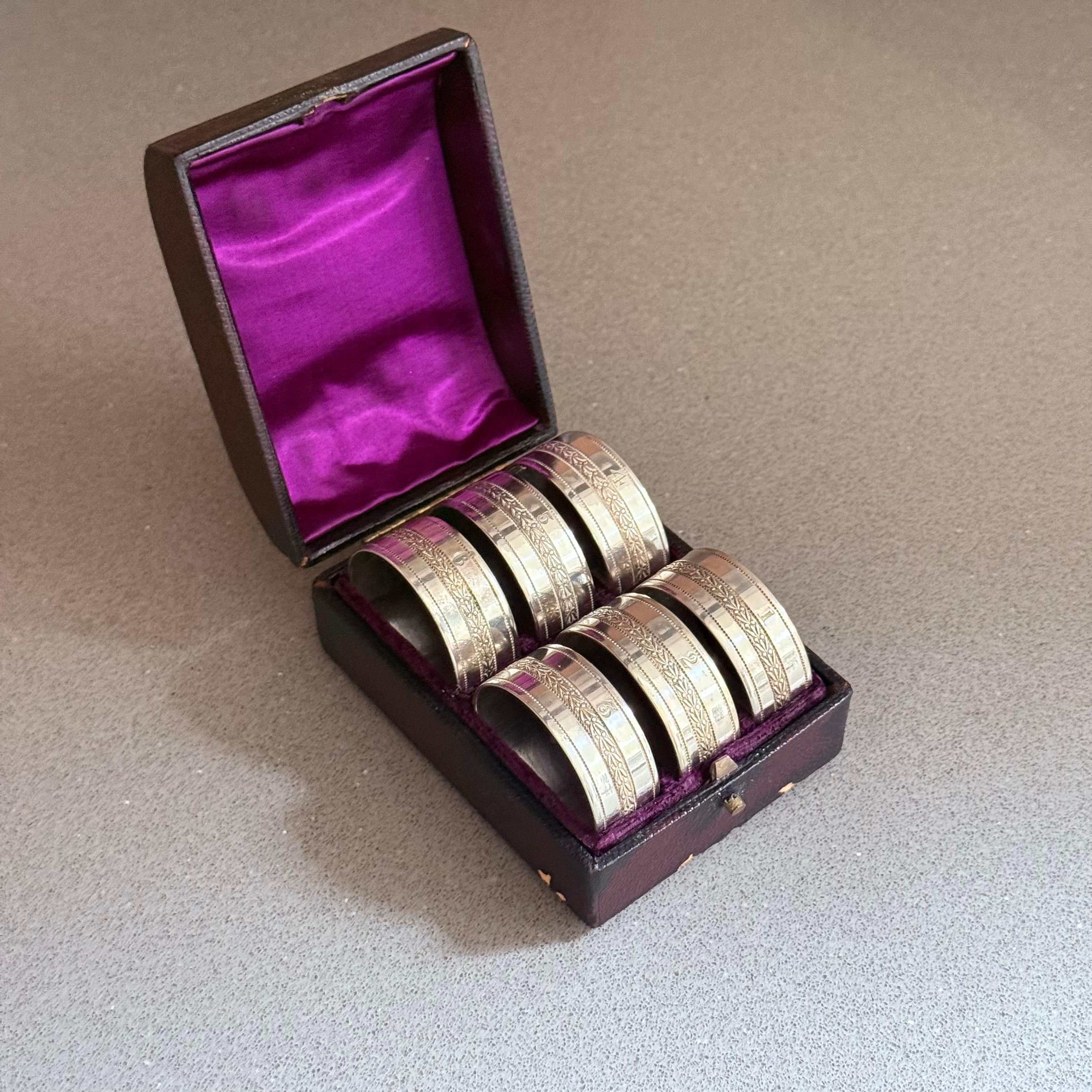 Eleganza per la tua esperienza culinaria con questo elegante set di 6 portatovaglioli antichi inglesi placcati in argento, splendidamente presentati nella loro custodia originale foderata in velluto. Ogni anello è finemente inciso con un motivo