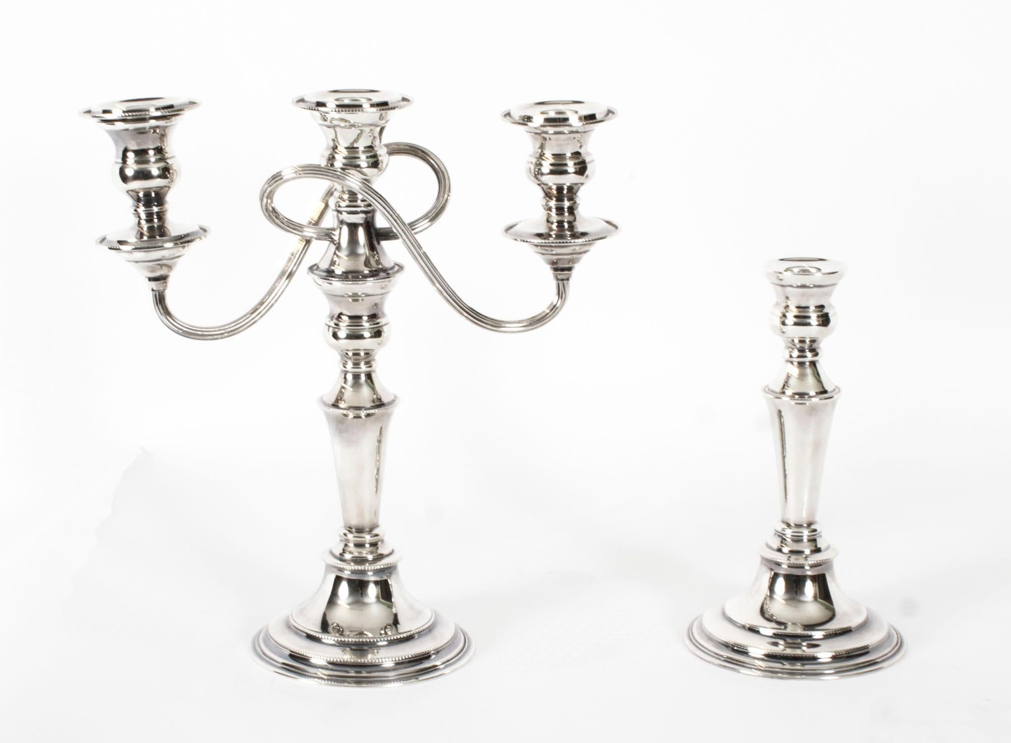 Pareja de candelabros ingleses de dos ramas, chapados en plata sobre cobre, cada uno con la marca del famoso platero Elkington & Co, fechados hacia 1920.

Las columnas centrales están estriadas con remates de hojas rígidas en la parte superior e