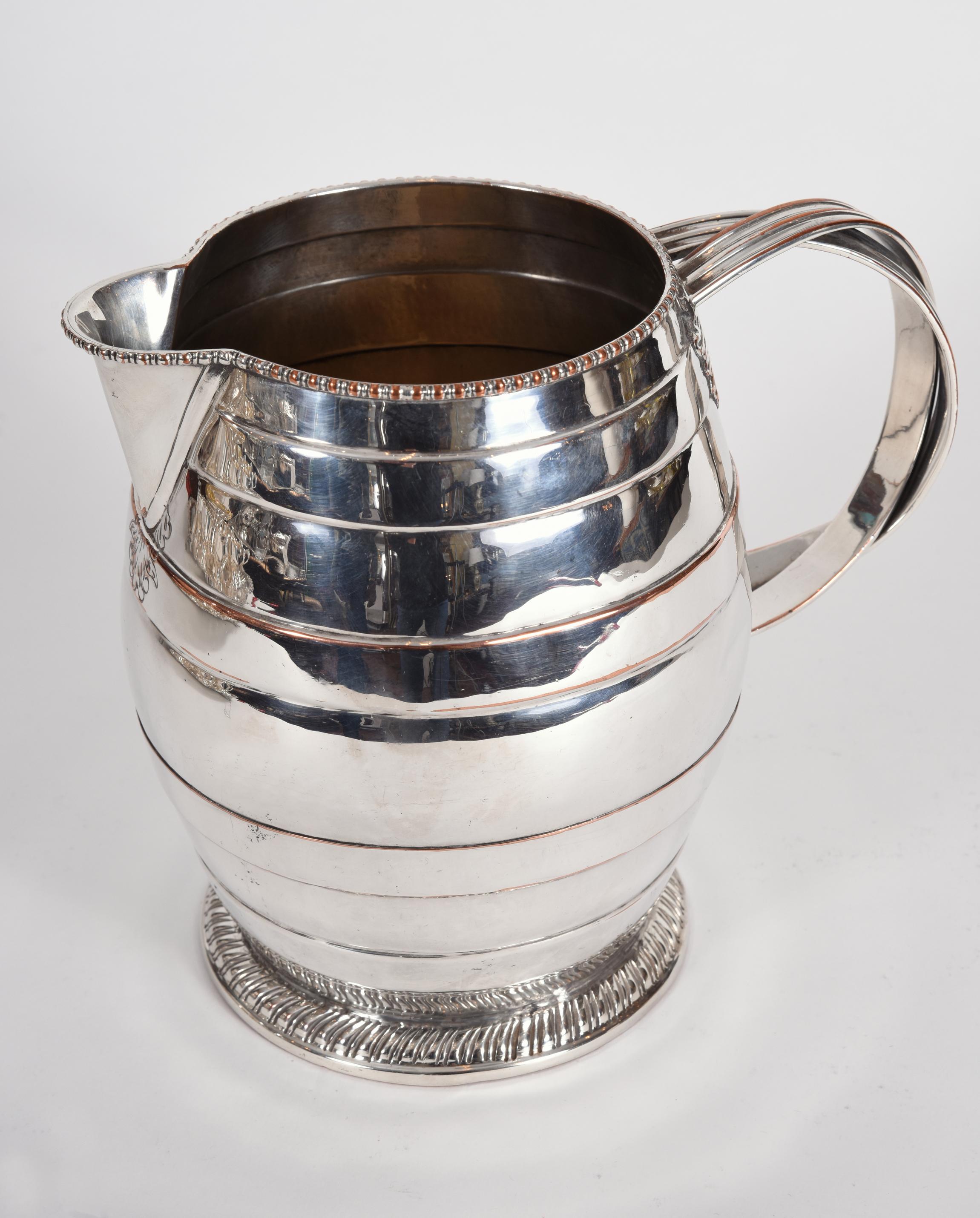 Antique English silver plated / copper tableware water pitcher with exterior design details and side handle. The pitcher is in excellent antique condition with minor wear due to age. The pitcher measure about 9 inches diameter x 7.5 inches high.
