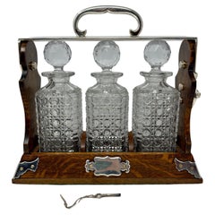 Antiguo tántalo inglés de plata y roble dorado de tres botellas, circa 1880.