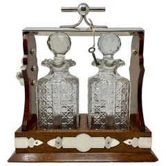 Antiguo Tántalo Inglés de Plata, Roble y Cristal Tallado de 2 Botellas, Circa 1890.