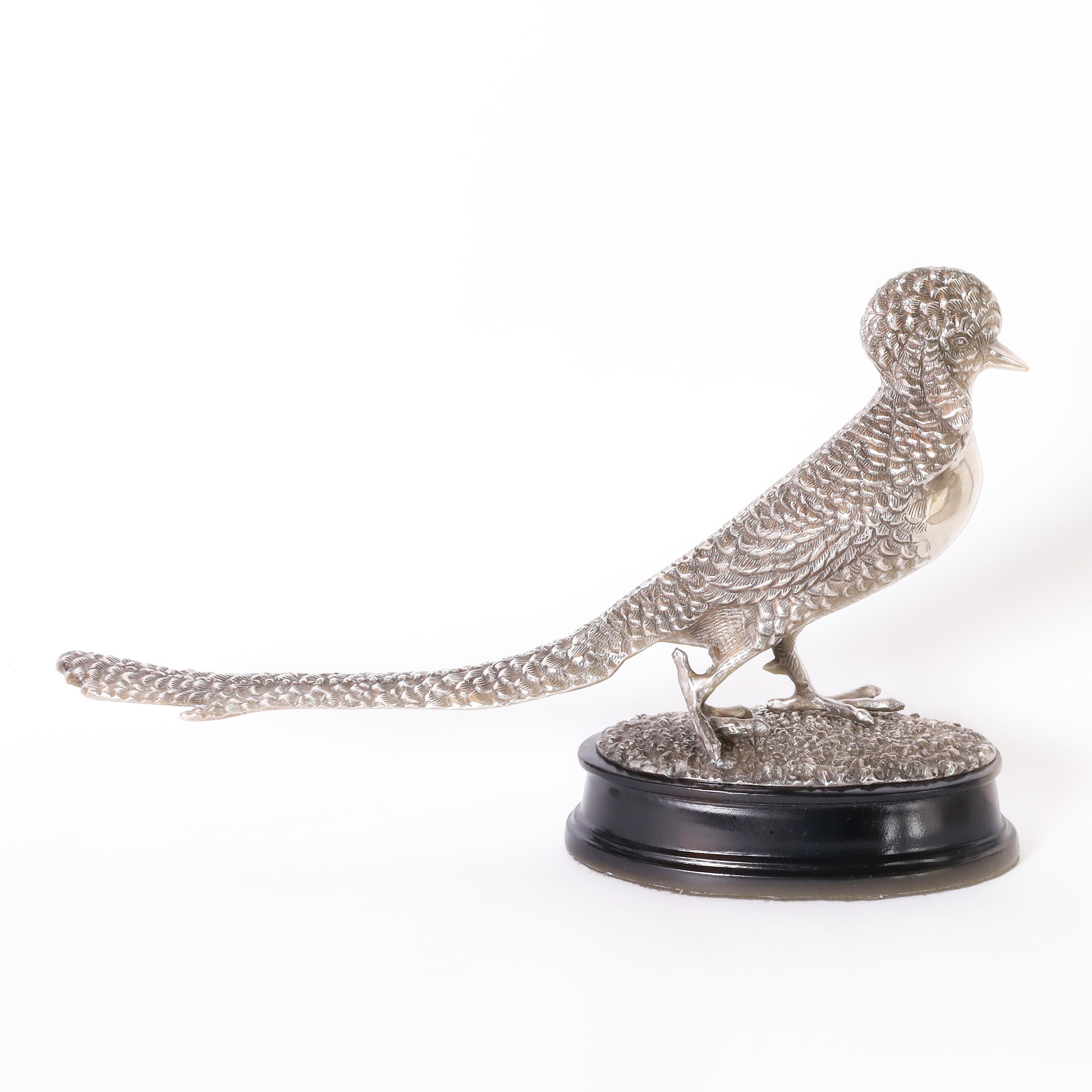 Lofty antique English pheasant figure or statuette crafted in silver plate on brass with ambitious detail and presented on a classic ebonized oval base.
