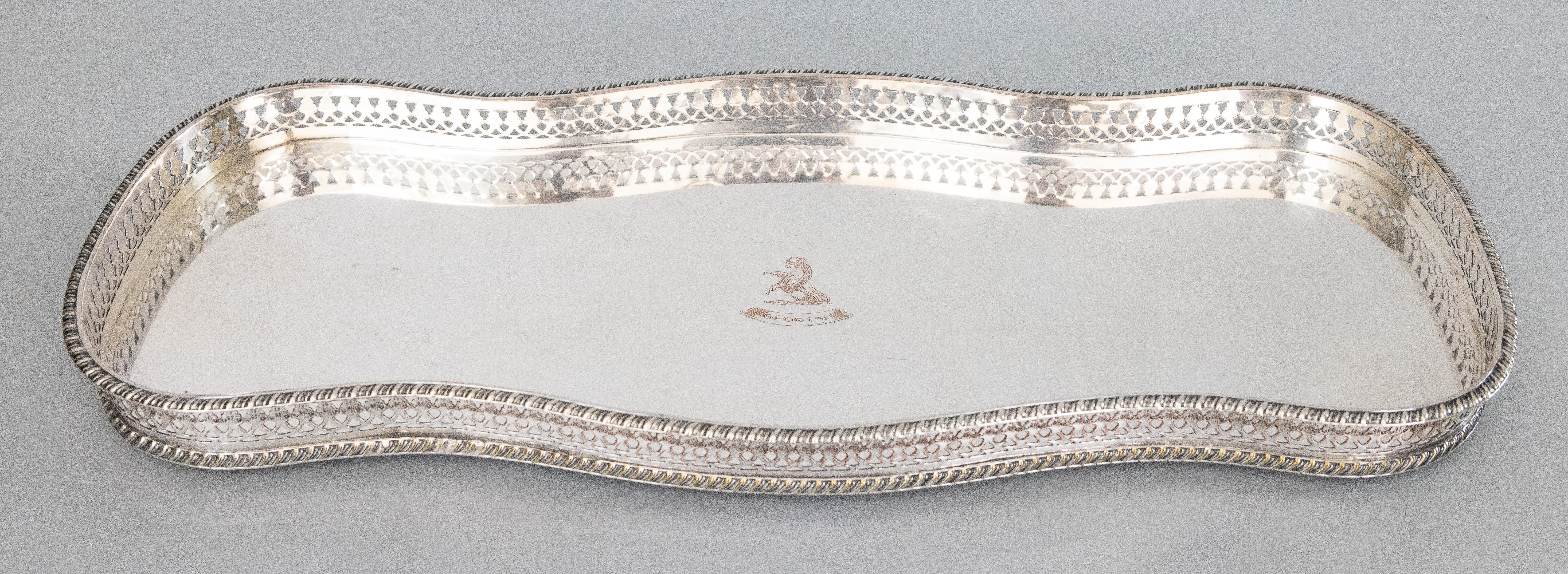 A fine antique English silverplate footed gallery serving or barware tray. Hallmarks on reverse. This gorgeous tray is solid and heavy with a lovely serpentine design, pierced gallery, and charming bun feet, perfect for serving or