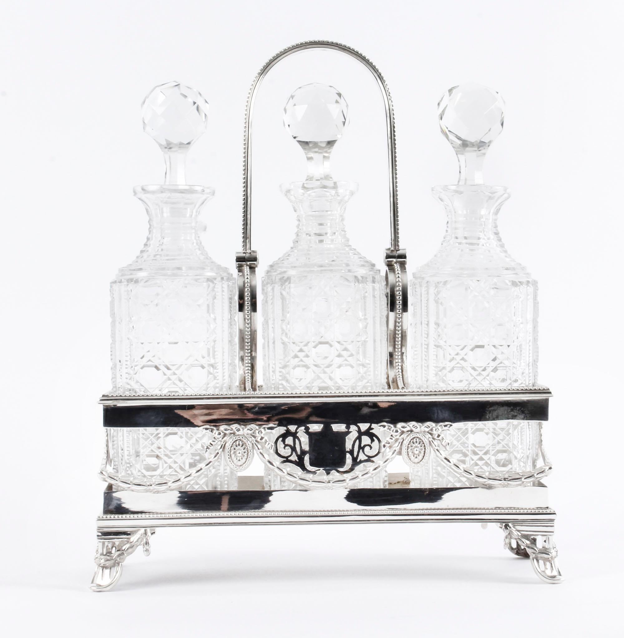 This is a truly resplendent antique Victorian silver-plated three crystal cut bottle tantalus set, circa 1880 in date. 

This magnificent tantalus set is by the renowned silversmiths Martin, Hall & Co of Sheffield, and retailed by the