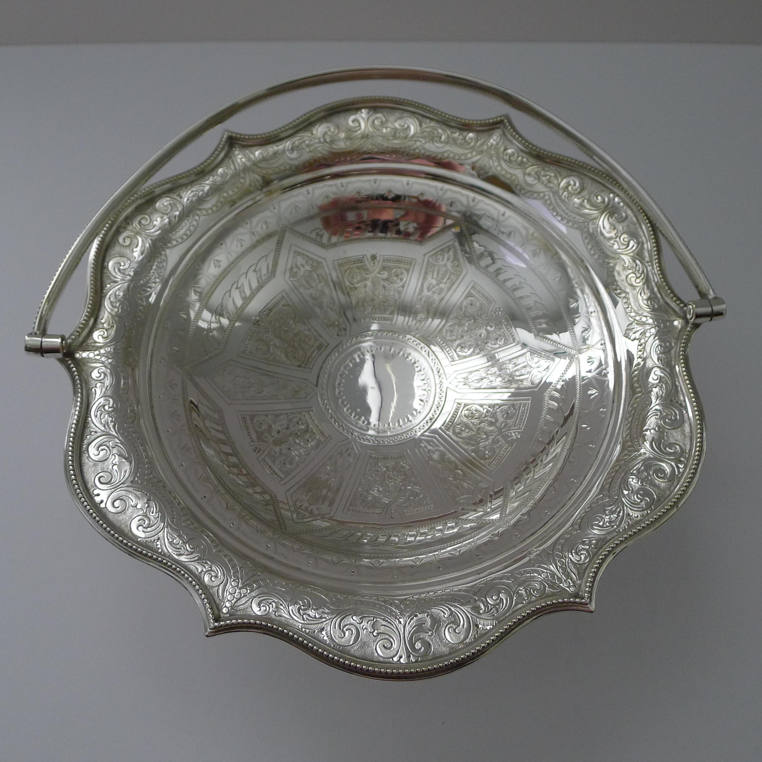 A stunning and highly decorative fruit or cake basket made from silver plate English in origin and Victorian in era.

Beautifully shaped, the footed basket has the most exquisite engraved decoration and has a folding swing handle.

The underside has