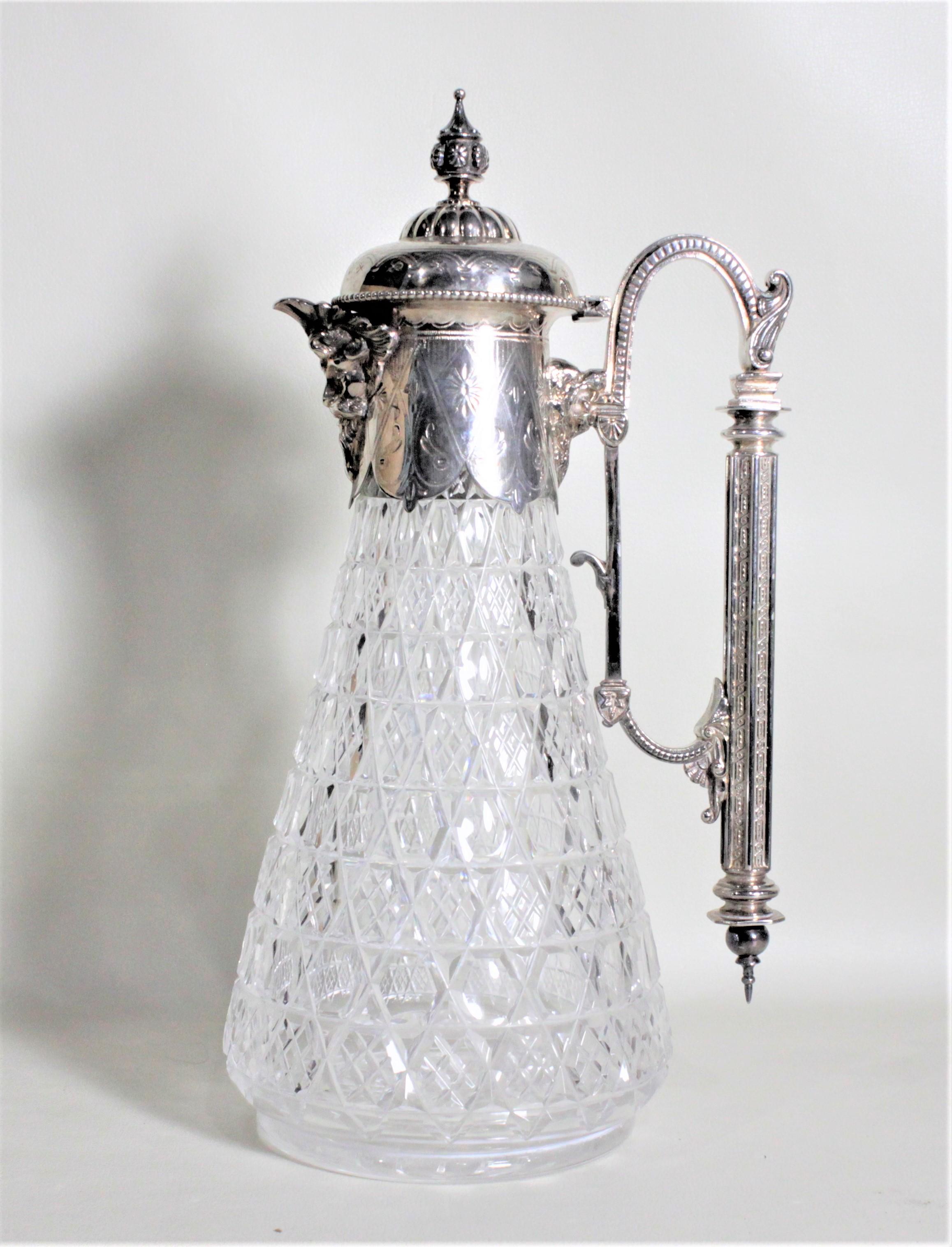 This antique silver plate and cut crystal claret jug was most likely made in England in circa 1900 in the Victorian style. The jug features a large silver plated handle and nice raised decoration around the banding at the top which accents the cut