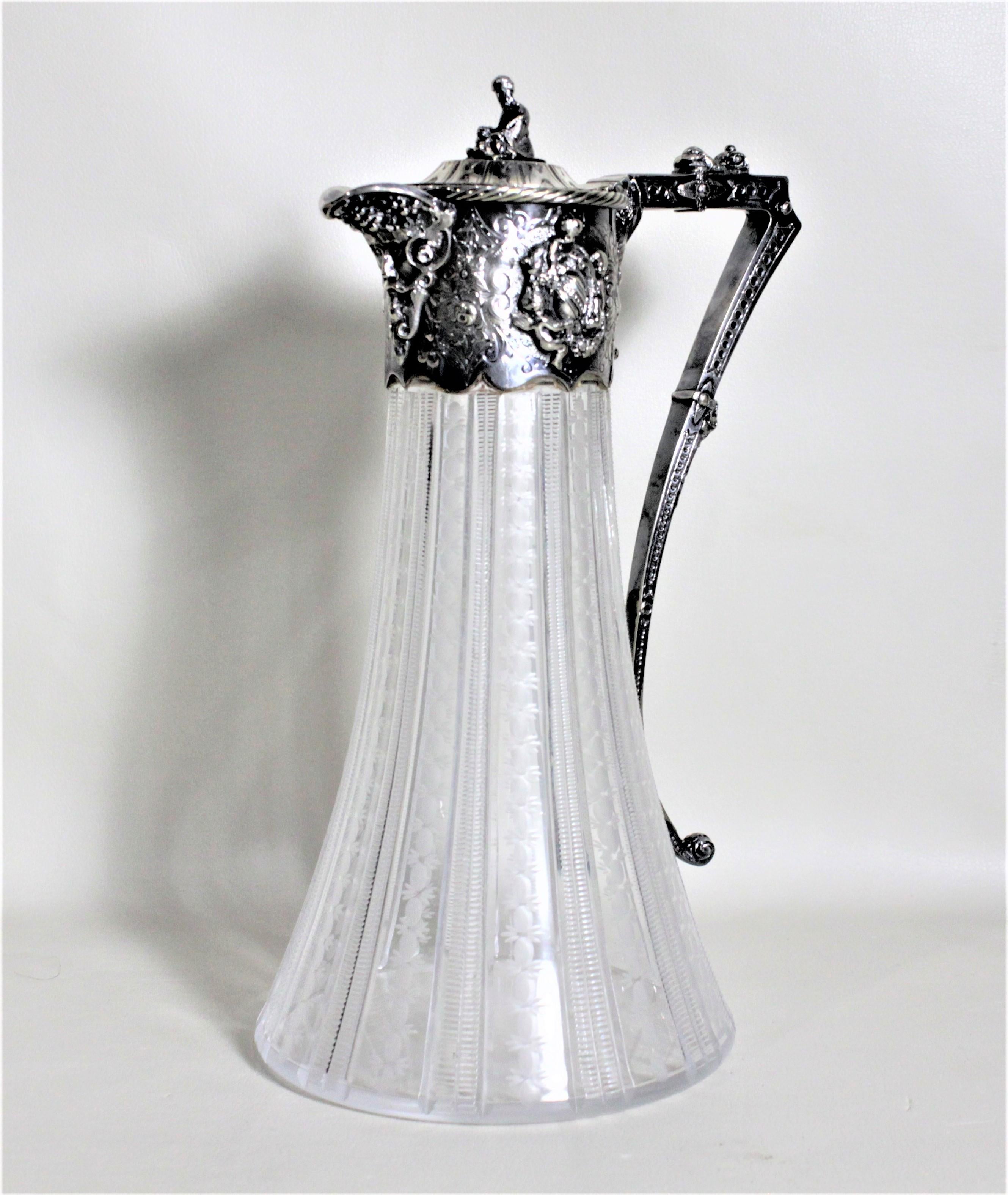 Dieser antike Krug aus Silberblech und geschliffenem Glas wurde höchstwahrscheinlich um 1900 in England im viktorianischen Stil hergestellt. Der Krug ist mit einer sitzenden Figur auf der Oberseite des Deckels und einem kunstvollen, erhabenen