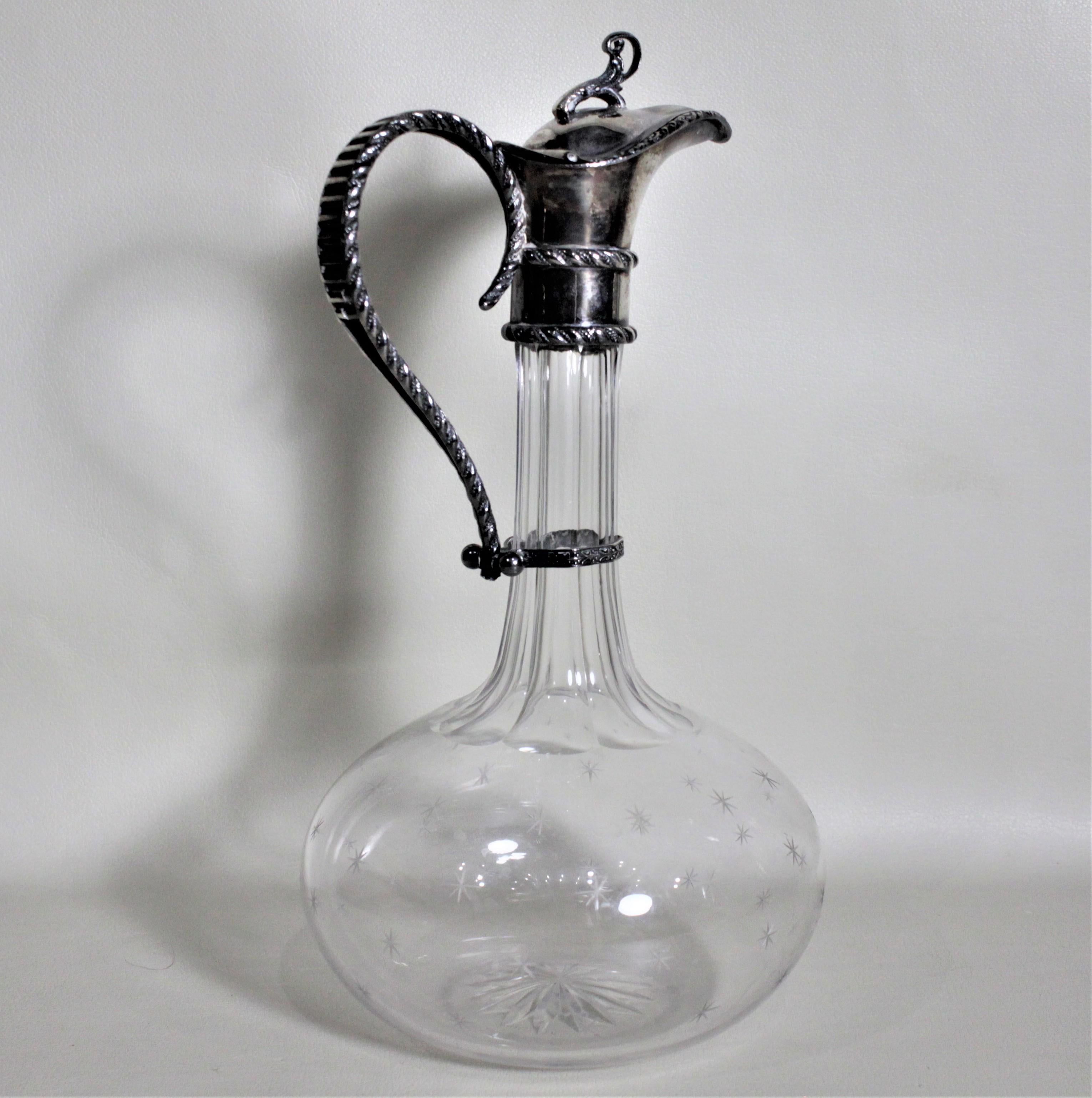 This antique silver plate and cut glass claret jug was most likely made in England in circa 1900 in the Victorian style. The jug features a simple looped finial on the cover of the deeply turned spout and a rope or raised garland motif around the