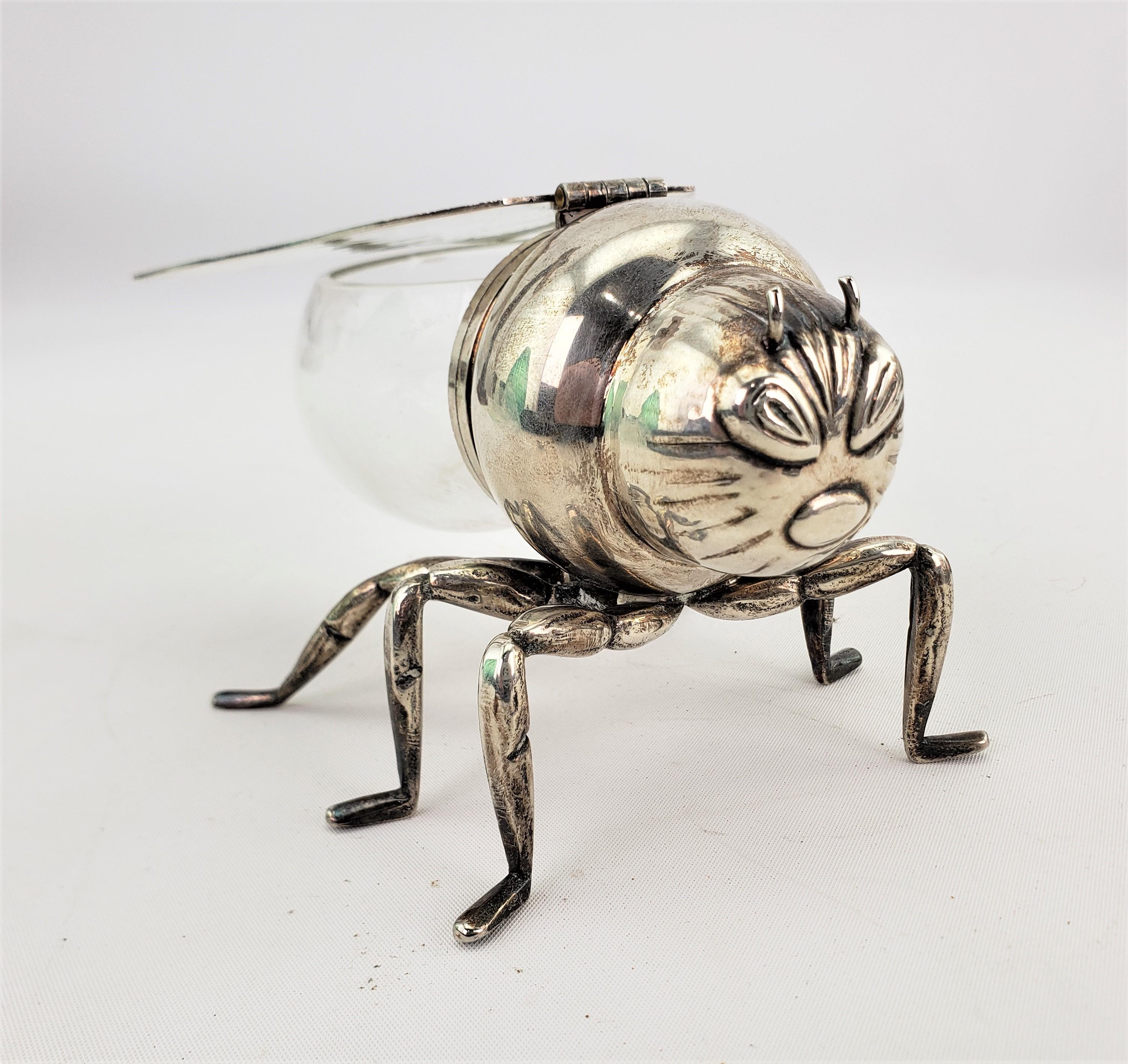 This antique silver plated and glass figural condiment server is unsigned, but presumed to have been made in England in approximately 1890-1900 in the period Victorian style. The silver plated and glass server is a stylized figural bee or wasp with